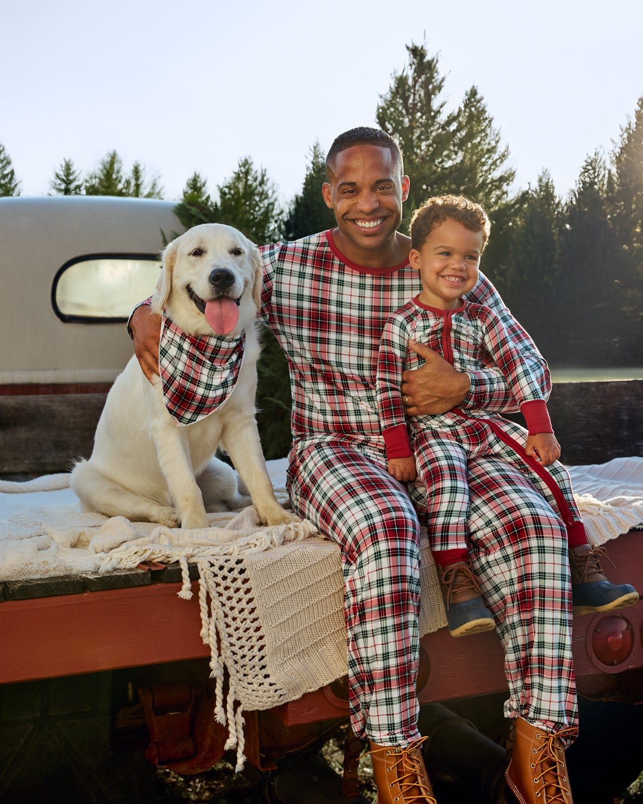 Father and son sitting on a truck bed wearing Holly Plaid pajamas