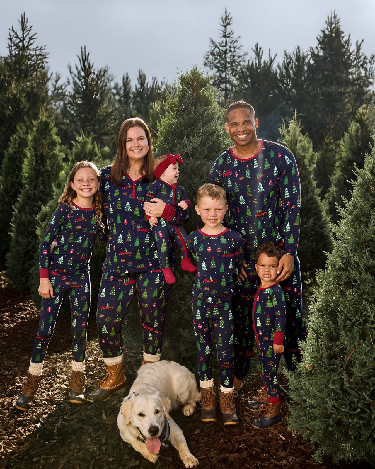 Family at the Christmas tree farm wearing matching Navy Tree Traffic pajamas
