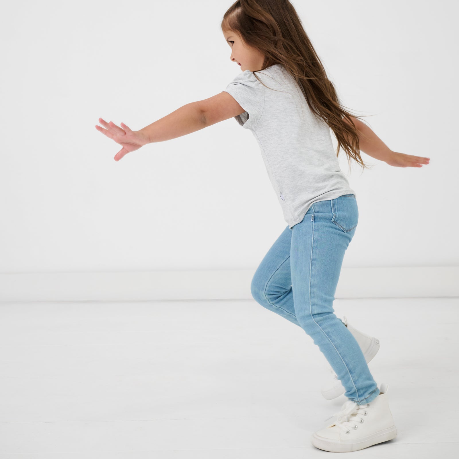 Child in motion wearing the Light Blue Denim Jegging with a light gray girls shirt