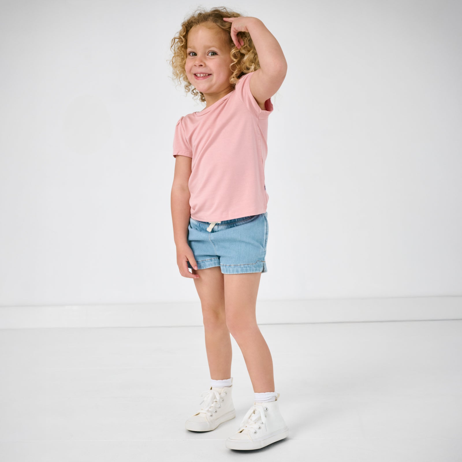 Girl wearing the Light Blue Denim Shorts with a blush pink puff sleeve top