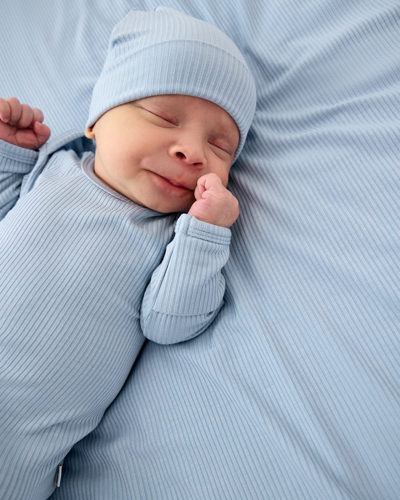 Newborn wearing the Light Fog Ribbed Infant Gown on a blue baby blanket