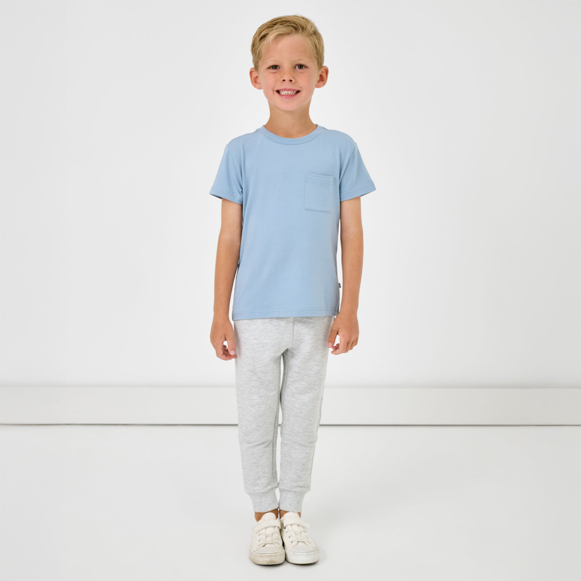 Standing boy wearing the Light Heather Gray Jogger with a blue pocket tee