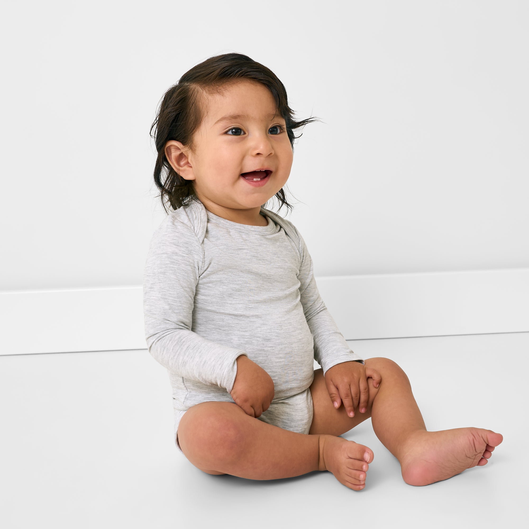 Sitting child wearing the Light Heather Gray Long Sleeve Bodysuit