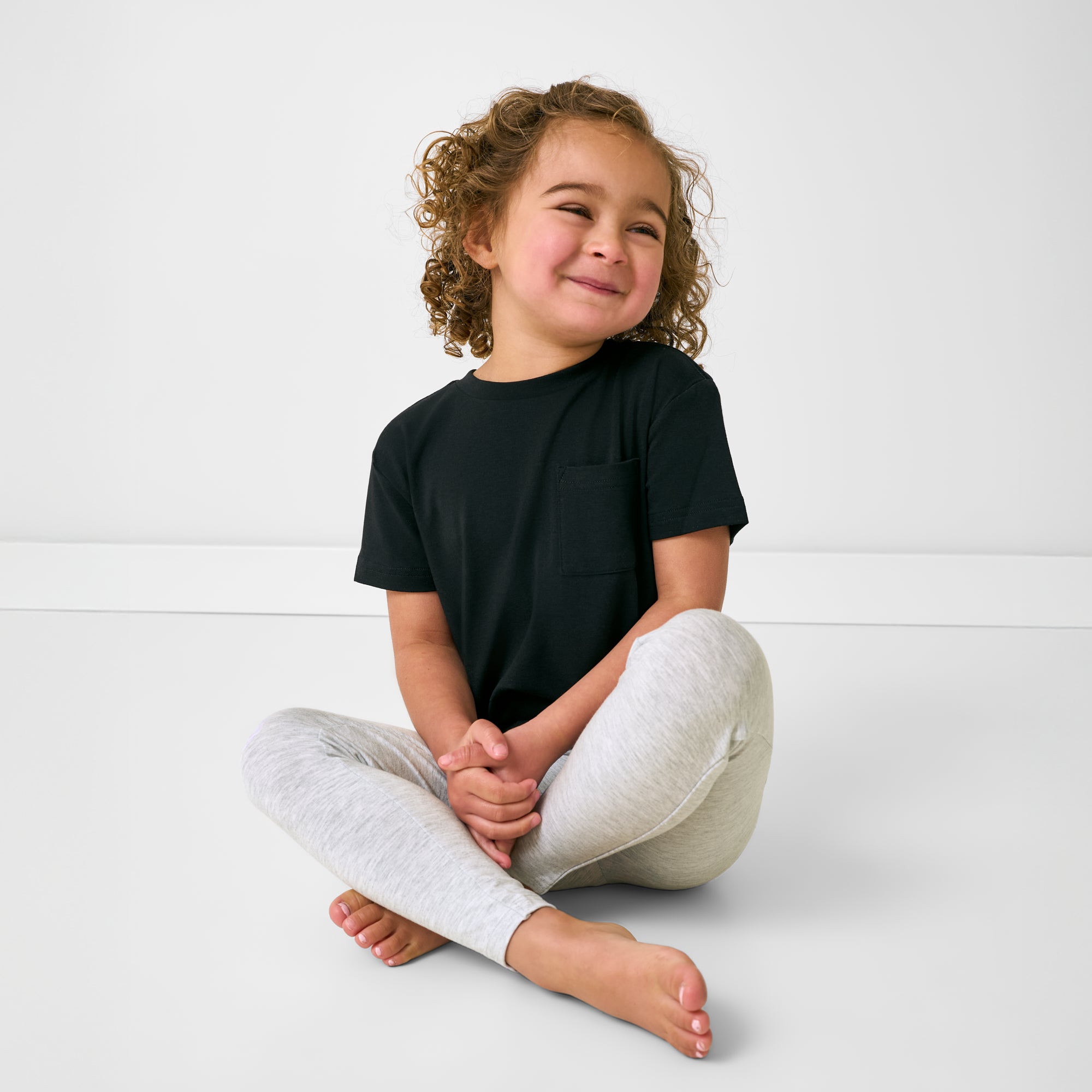 Sitting girl wearing the Light Heather Gray Legging and black tee