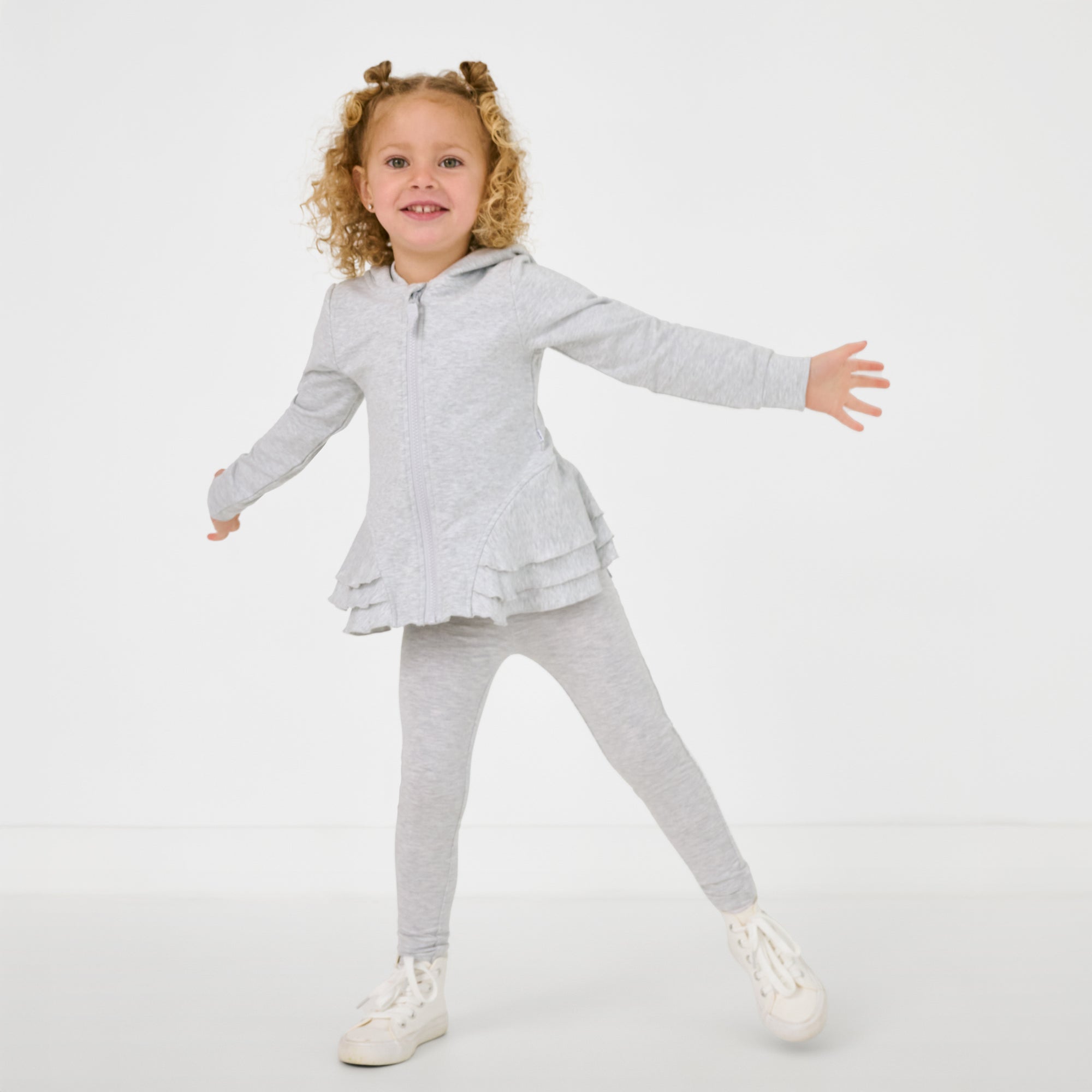 Posing child wearing the Light Heather Gray Peplum Hoodie with matching leggings