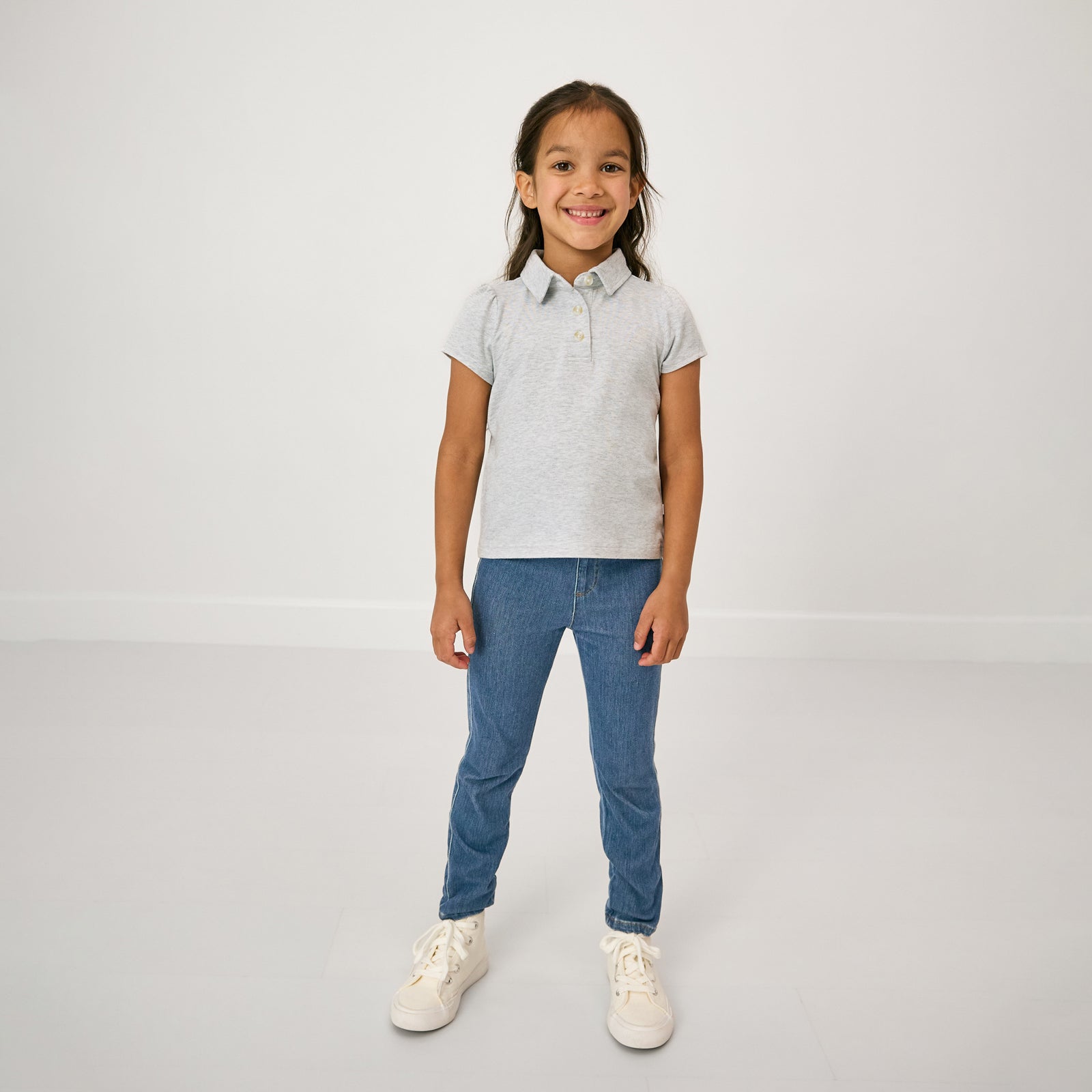 Standing child wearing the Light Heather Gray Puff Sleeve Polo and blue denim jeggings
