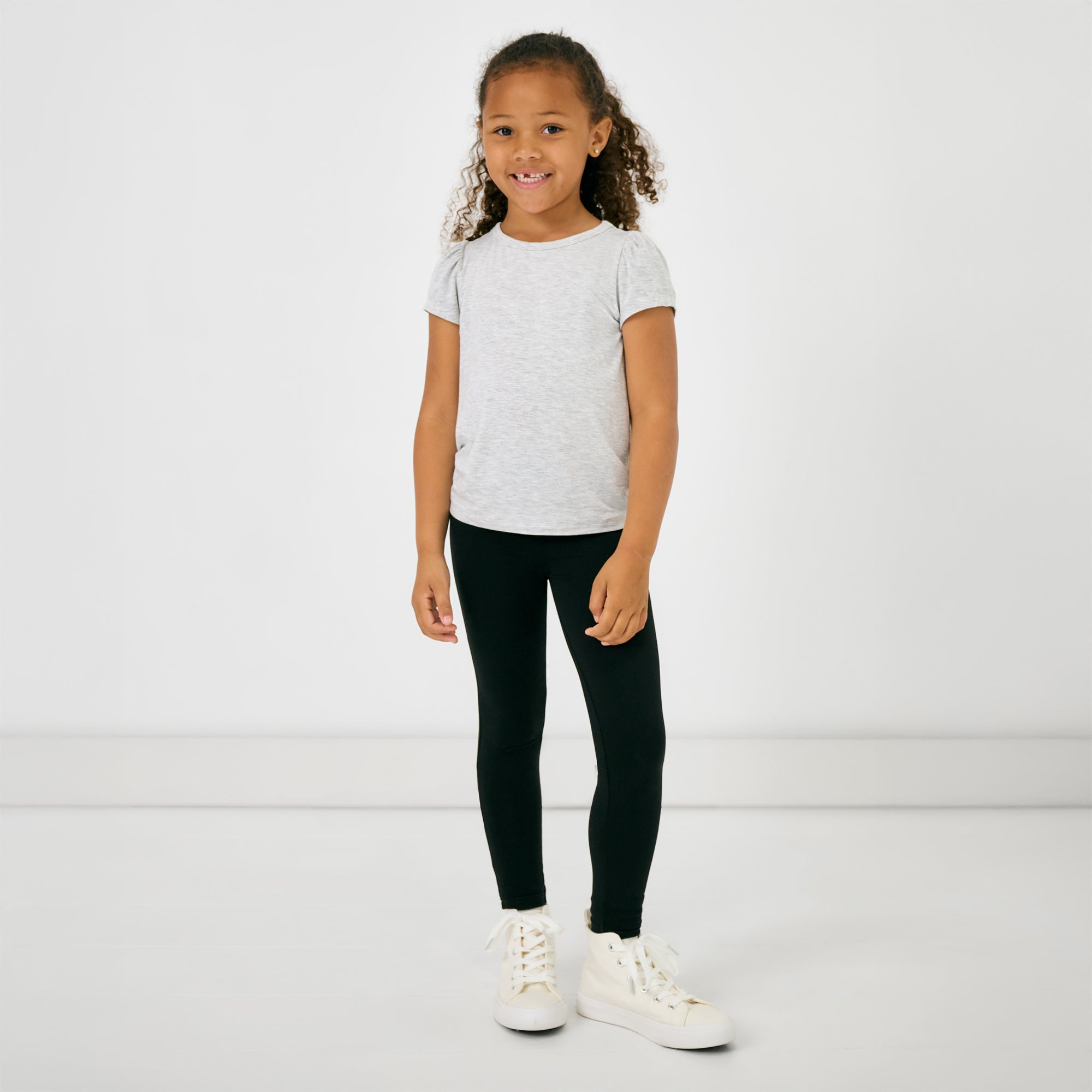 Standing child wearing the Light Heather Gray Puff Sleeve Tee with black leggings