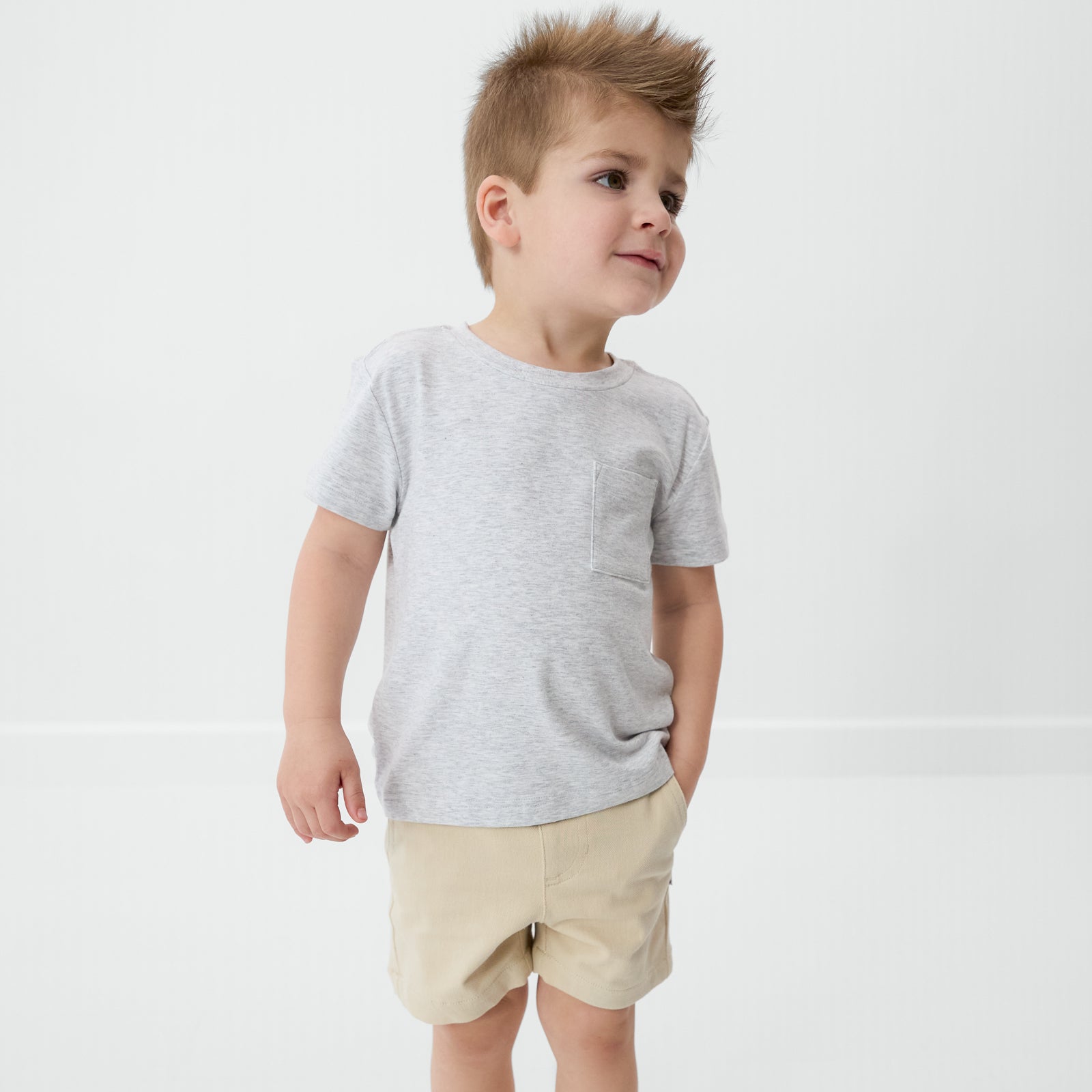 Child wearing the Light Heather Gray Relaxed Pocket Tee paired with light khaki chino shorts