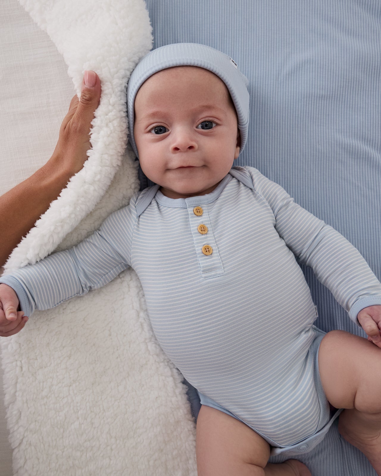 Baby wearing the Light Fog Stripe Henley Bodysuit on a blue baby blanket