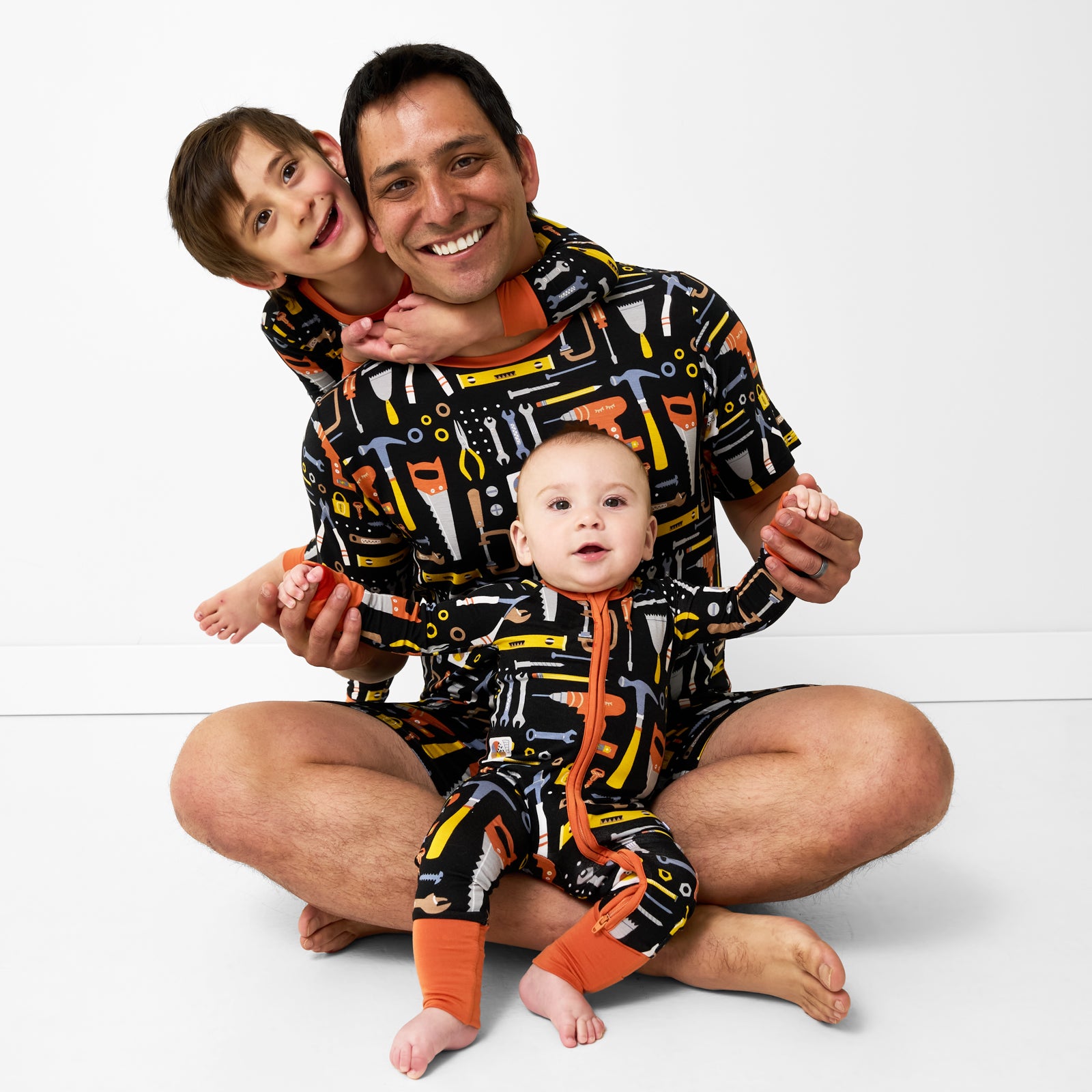 Father and two children wearing matching Little Builders pajamas