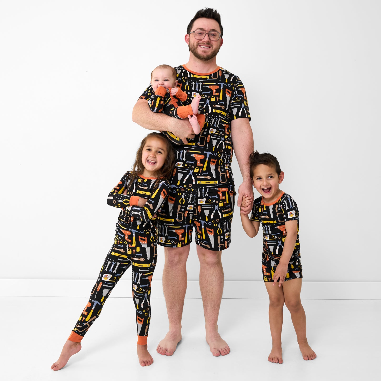 Father and three children wearing matching Little Builders pajamas