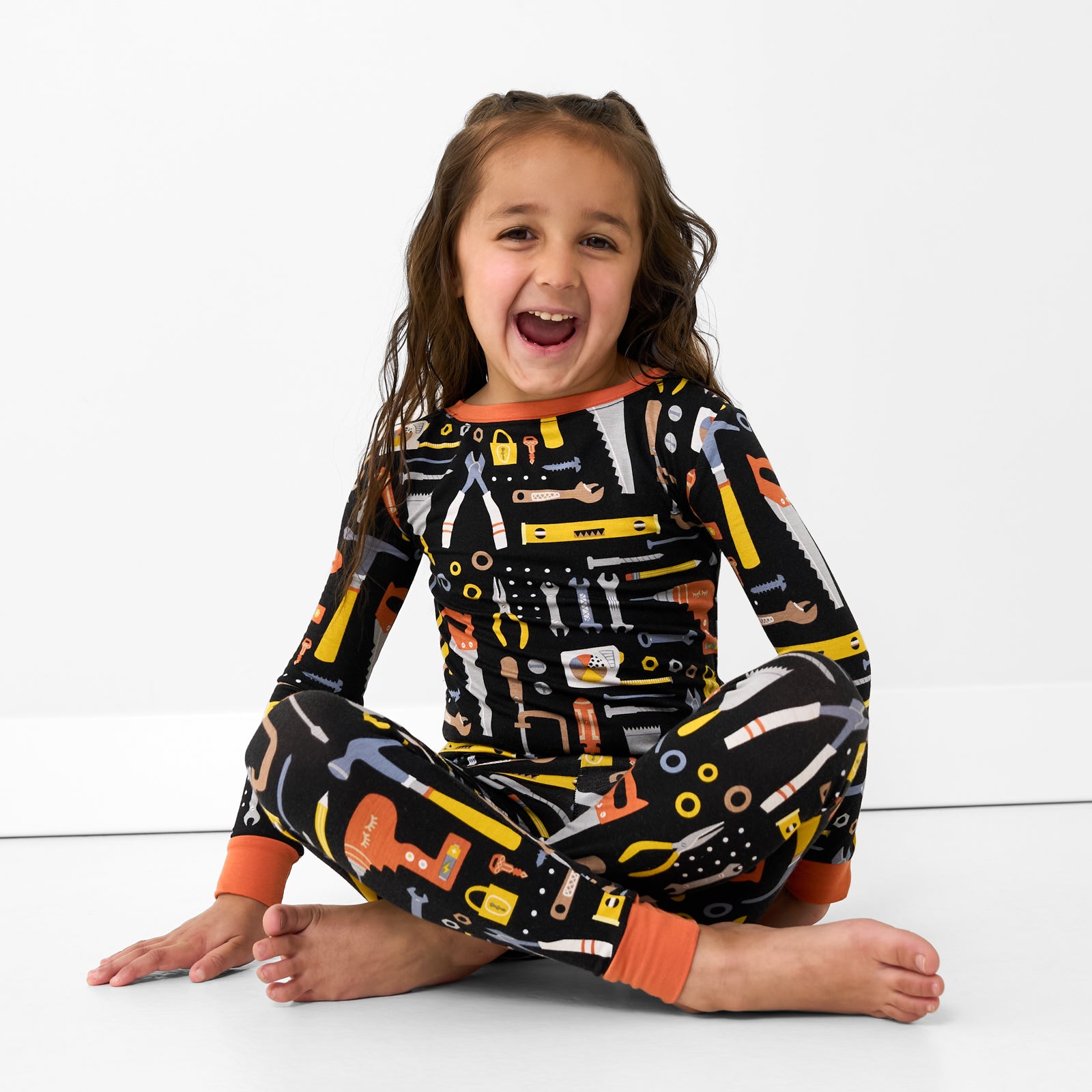 Sitting child wearing the Little Builders Two-Piece Pajama Set