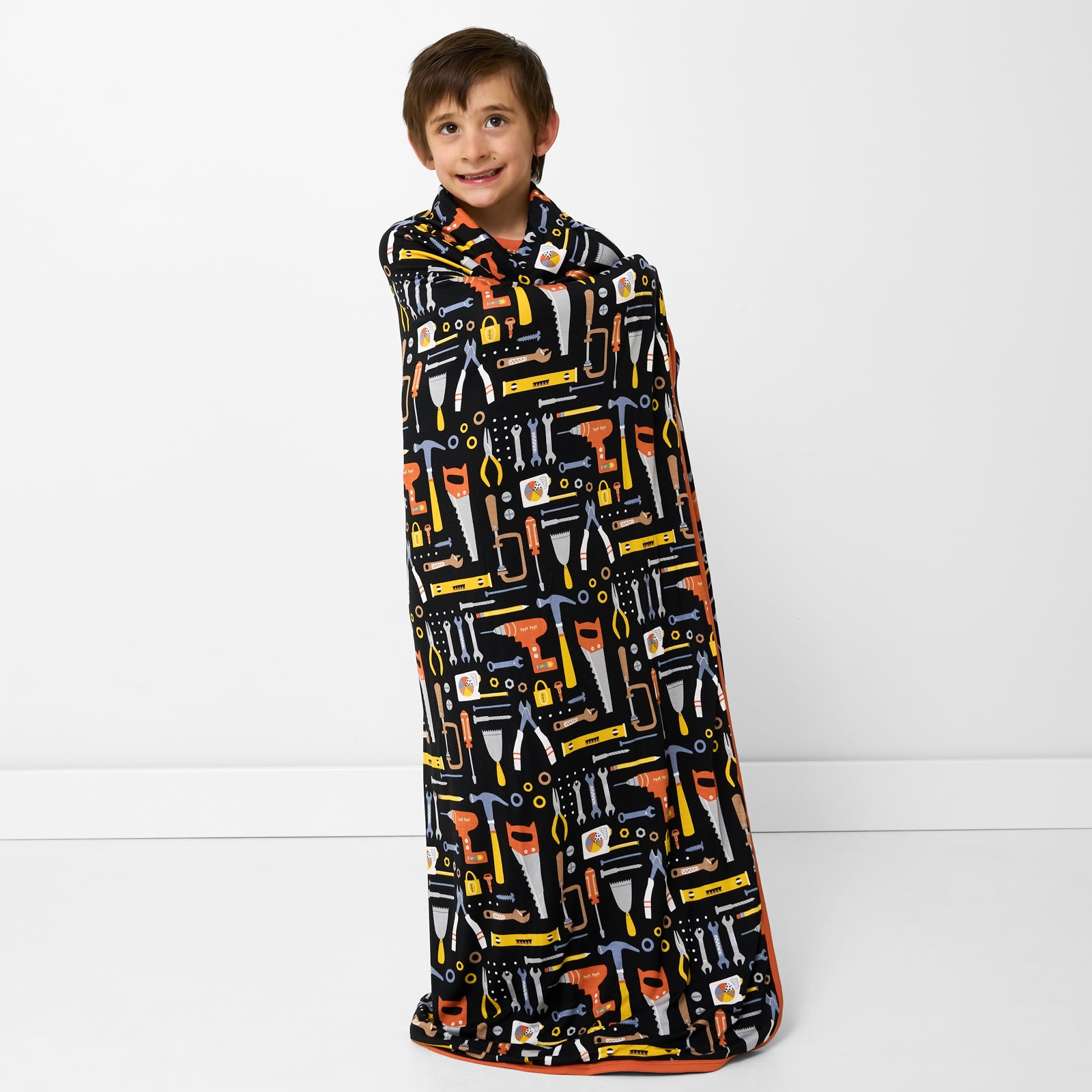 Standing child wrapped in the Little Builders Large Cloud Blanket®