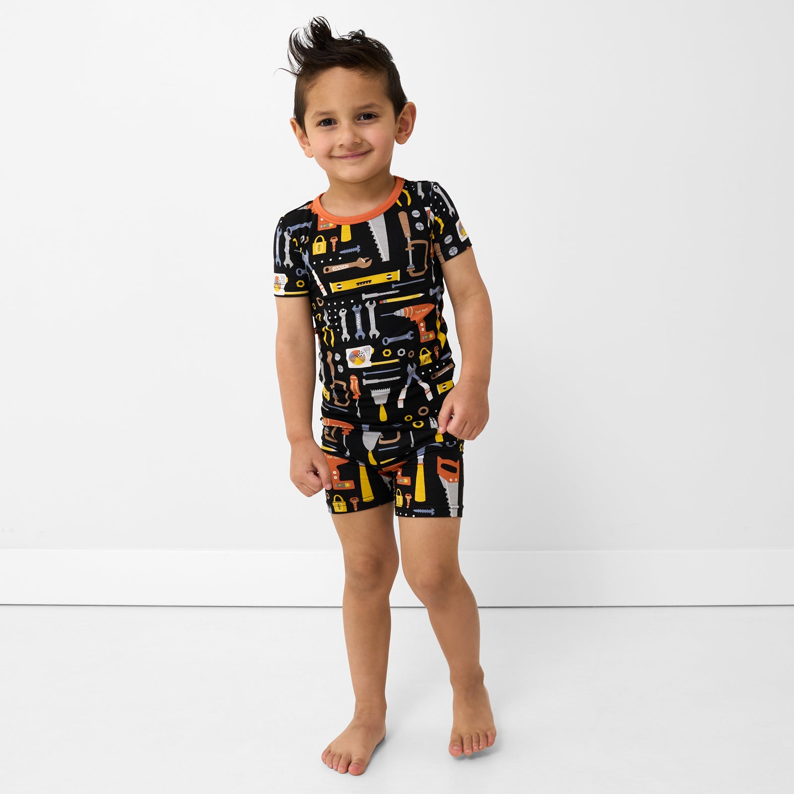 Standing child wearing the Little Builders Two-Piece Short Sleeve & Shorts Pajama Set