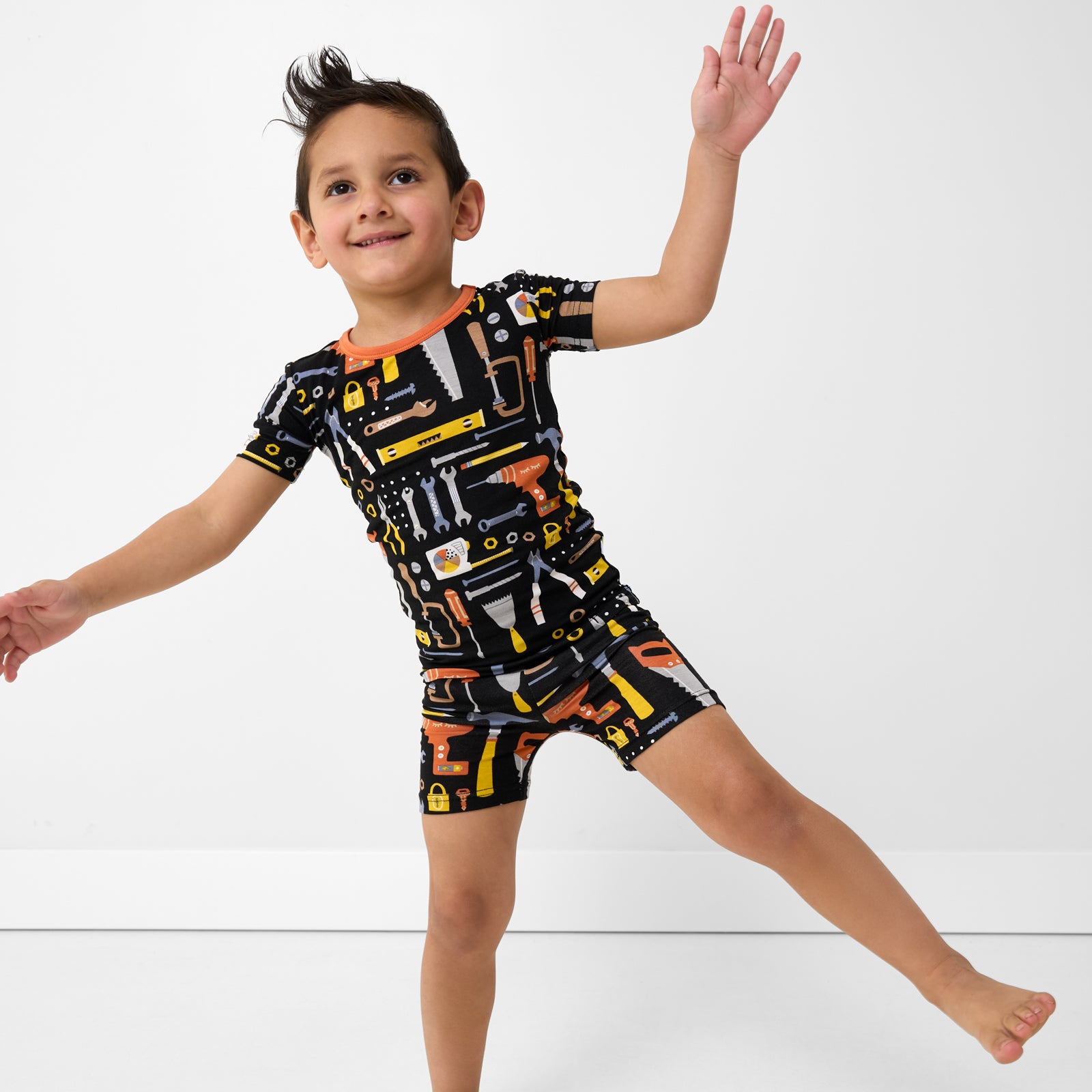 Posing child wearing the Little Builders Two-Piece Short Sleeve & Shorts Bamboo Pajama Set