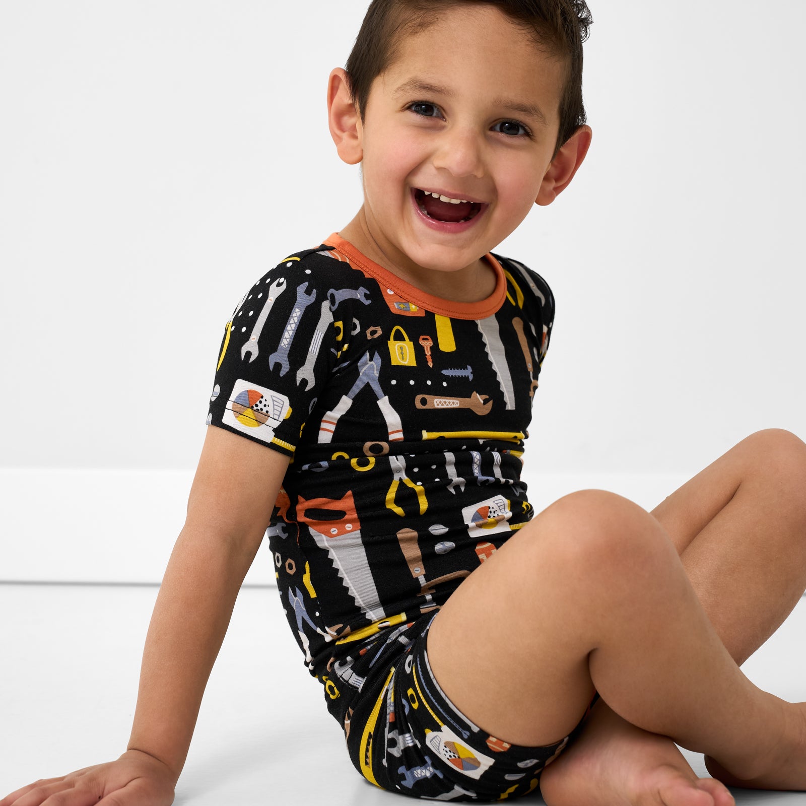 Sitting child wearing the Little Builders Two-Piece Short Sleeve & Shorts Pajama Set