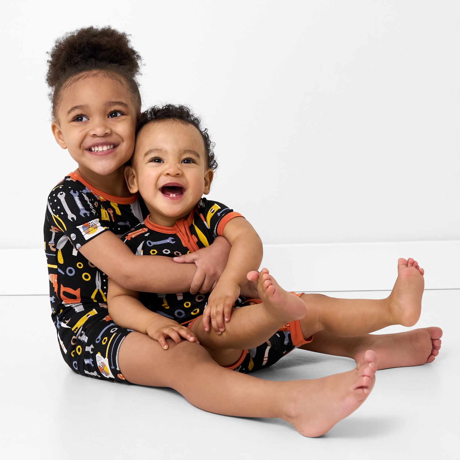 Two children wearing matching Little Builders pajamas