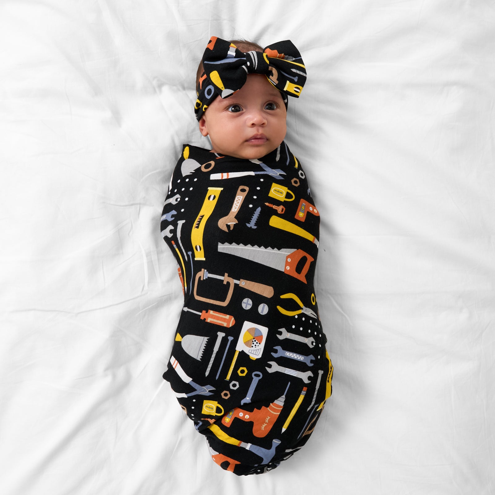 Aerial view of child wearing the Little Builders Swaddle & Luxe Bow Headband Set