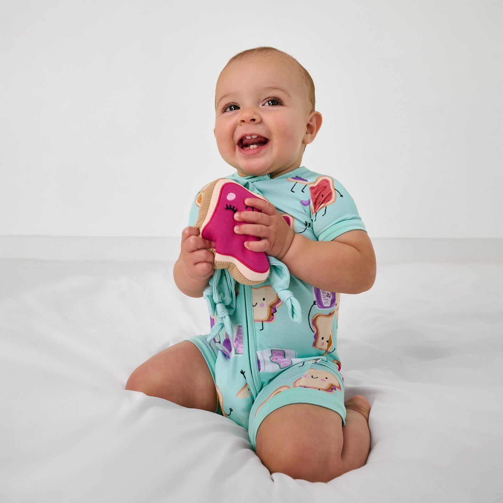 Sitting child wearing the Lunch Buddies Shorty Zippy holding the PB and J lovey