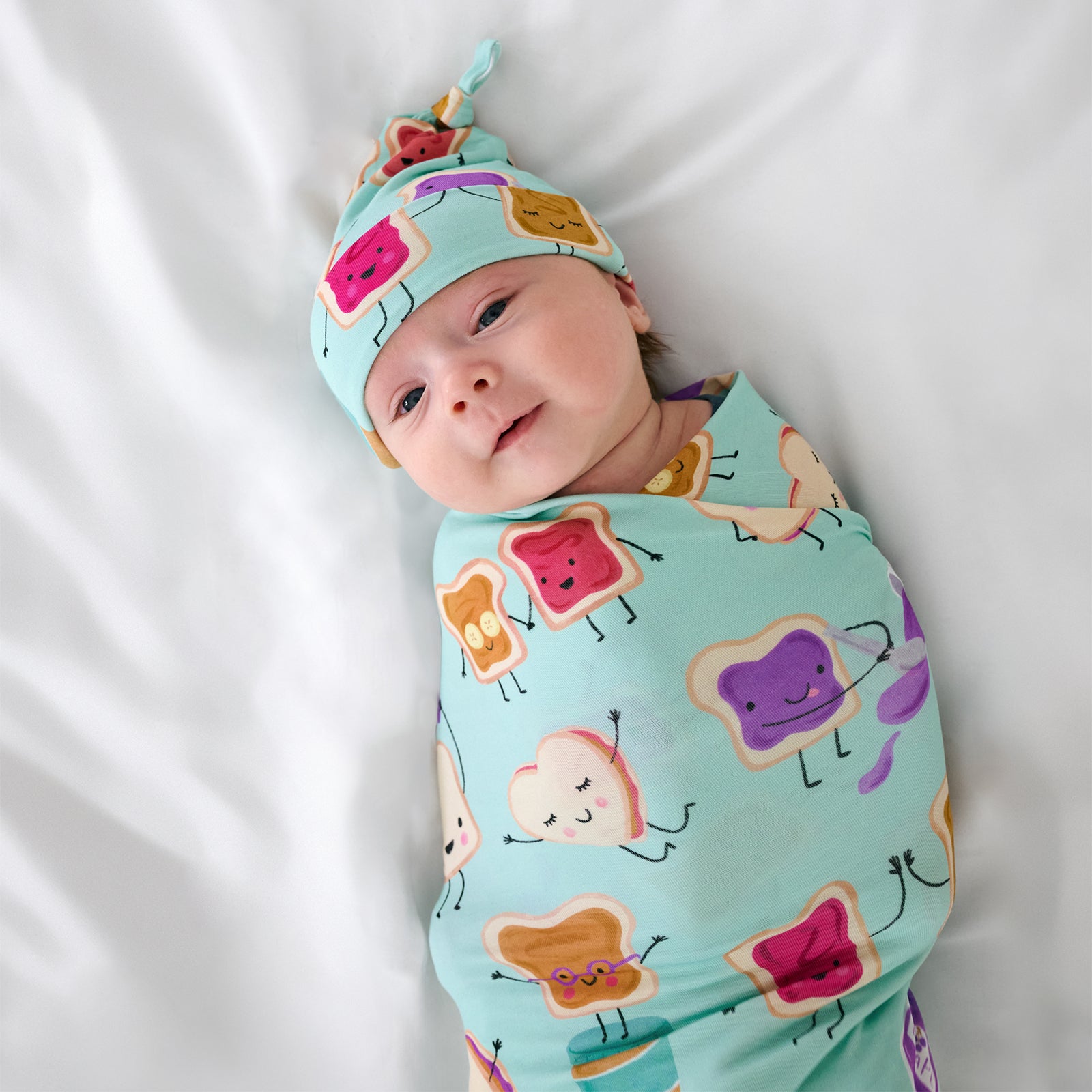 Close up aerial view of child wearing the Lunch Buddies Swaddle & Hat Set