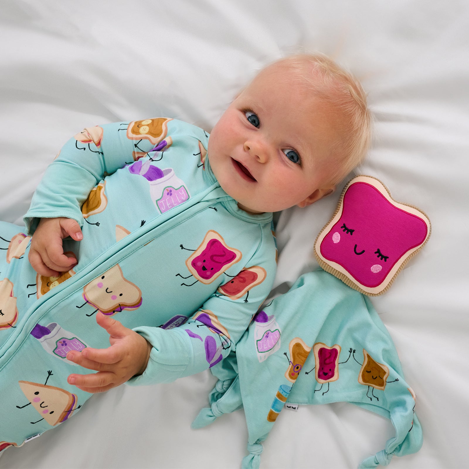Alternate aerial view of child laying with the Sammie the PB & J Sleepyhead Lovey