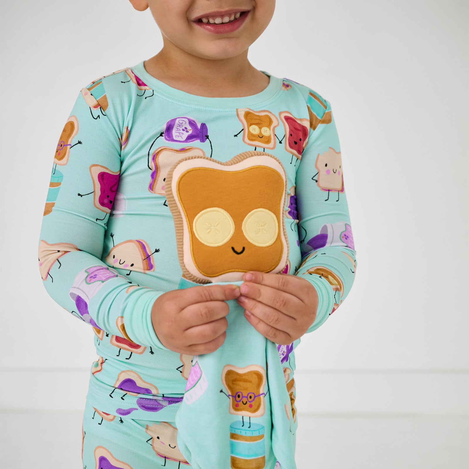 Child holding up the peanut butter side of the Sammie the PB & J Sleepyhead Lovey