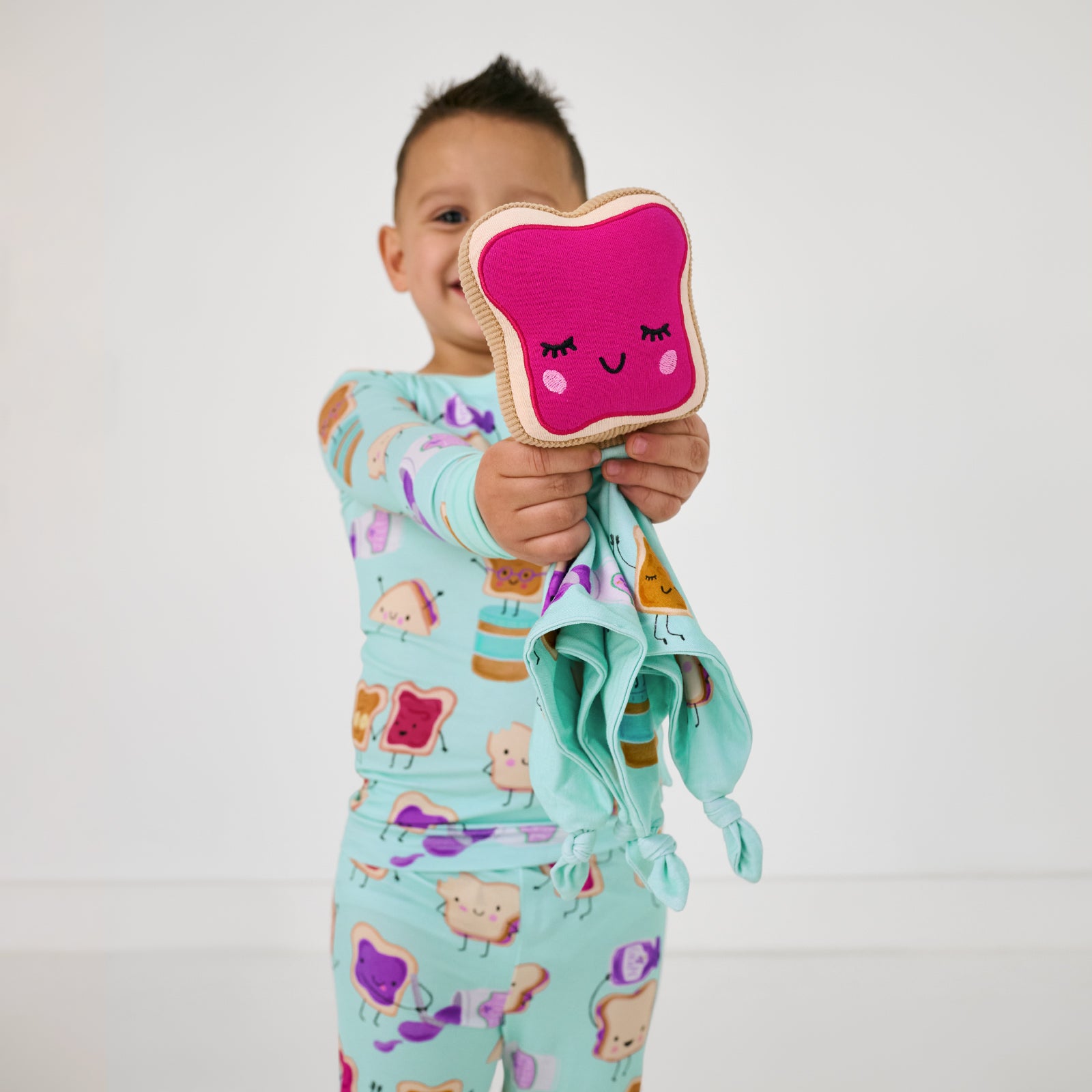 Child holding up the jelly side of the Sammie the PB & J Sleepyhead Lovey