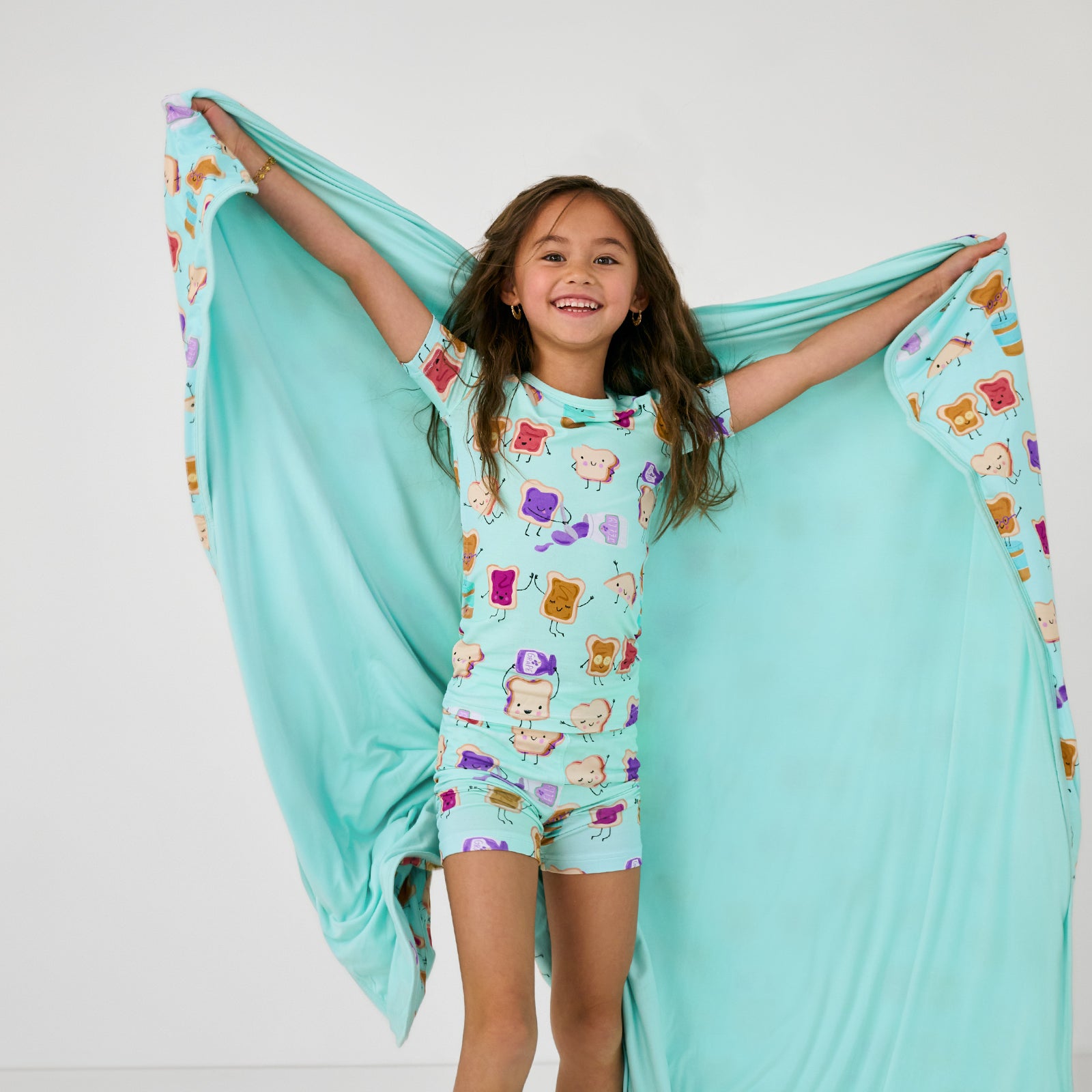 Standing child holding up the Lunch Buddies Large Cloud Blanket® showing the solid mint green side