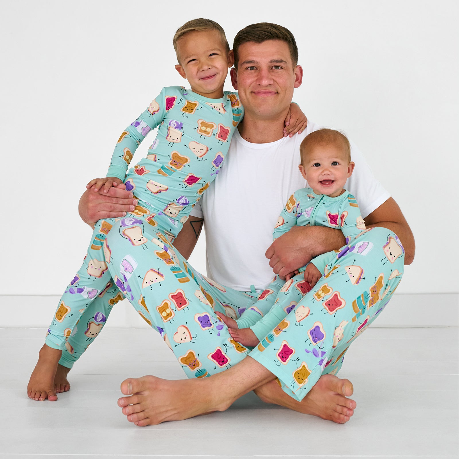 Sitting man and two children wearing matching Lunch Buddies bamboo pjs
