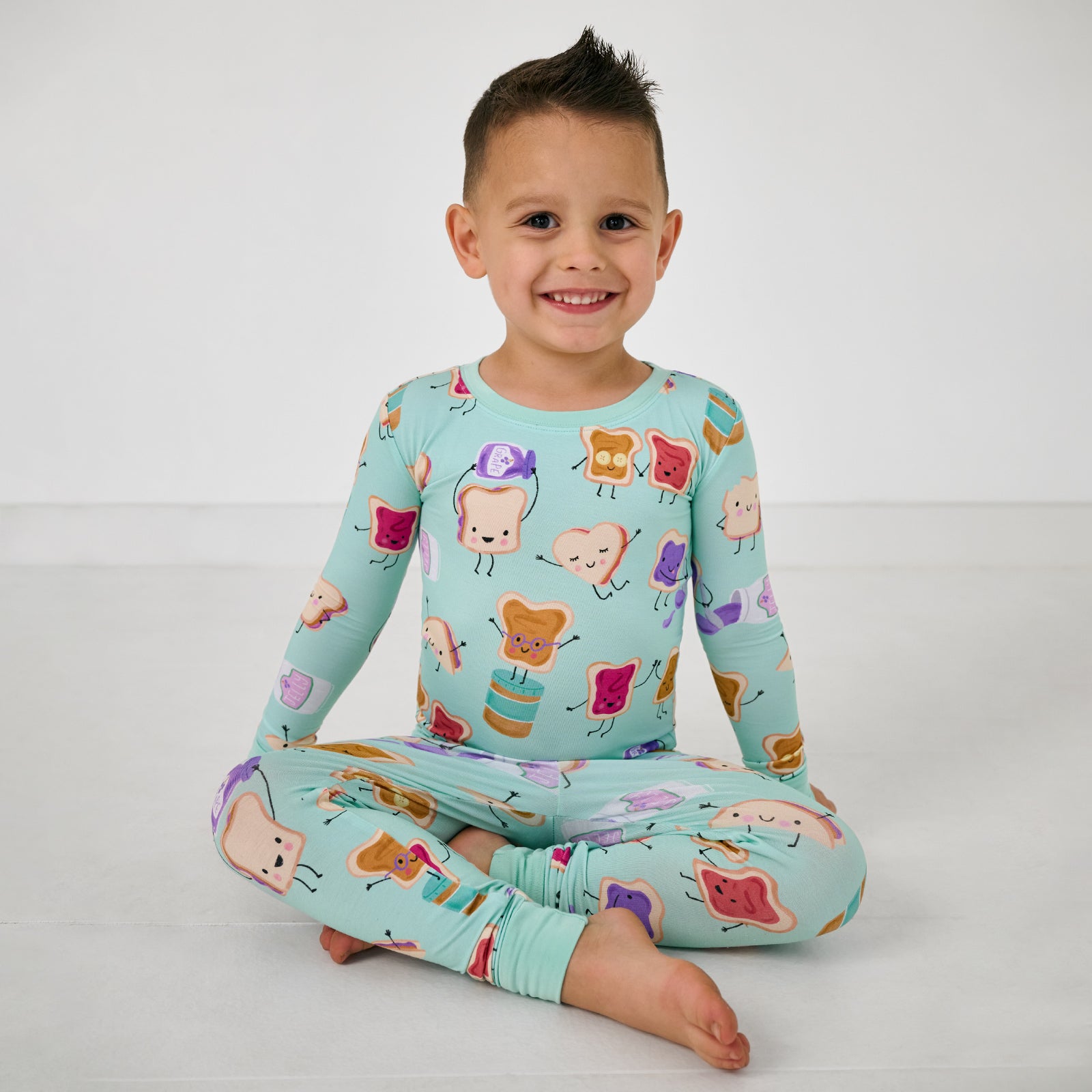 Sitting child wearing the Lunch Buddies Two-Piece Pajama Set