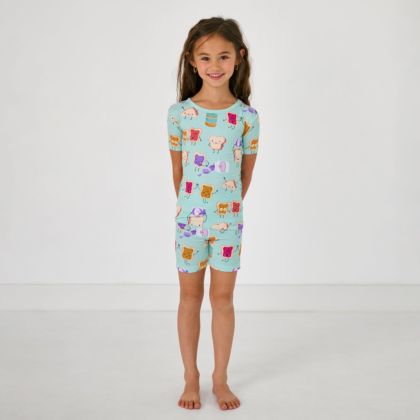 Standing child wearing the Lunch Buddies Two-Piece Short Sleeve & Shorts Pajama Set
