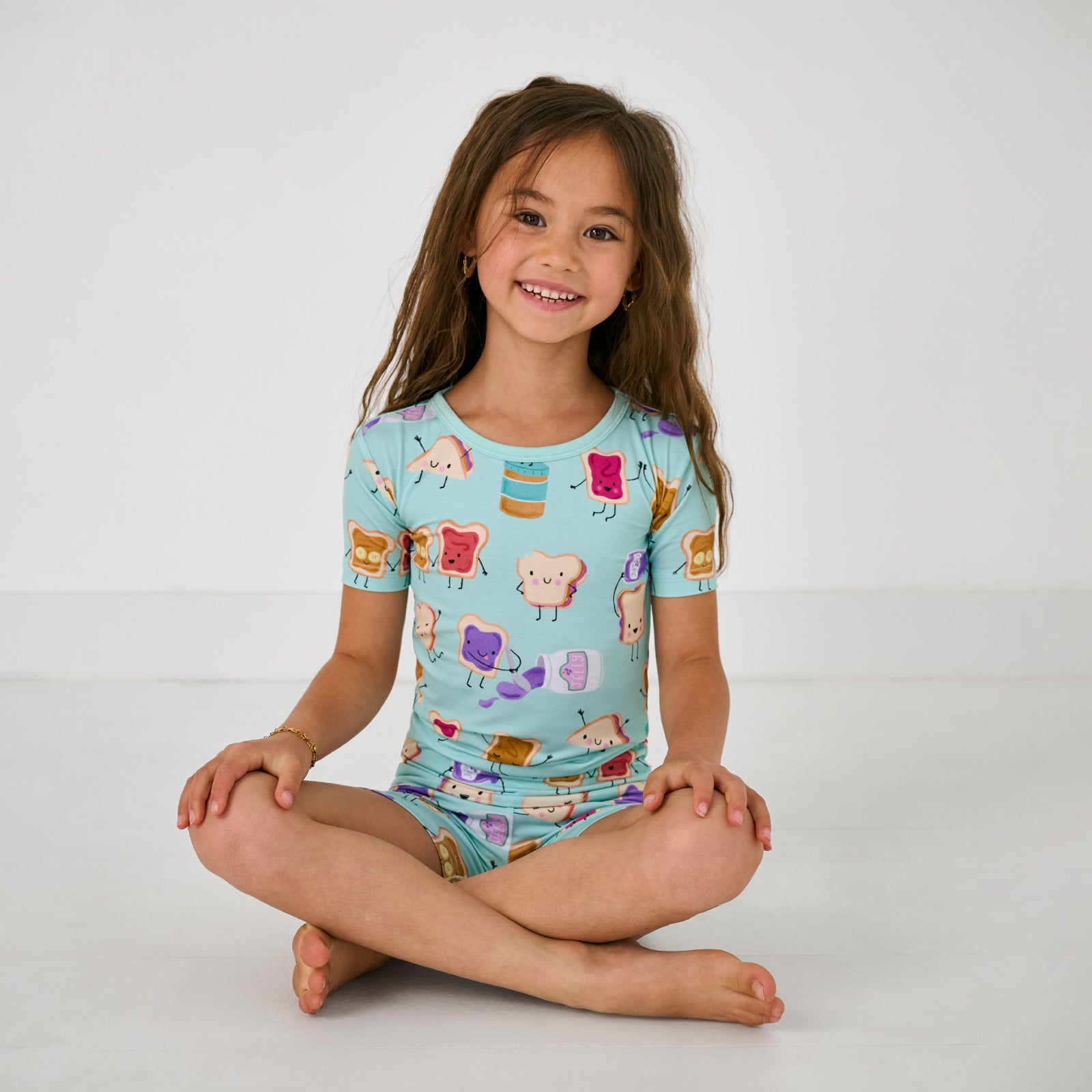 Sitting child wearing the Lunch Buddies Two-Piece Short Sleeve & Shorts Pajama Set