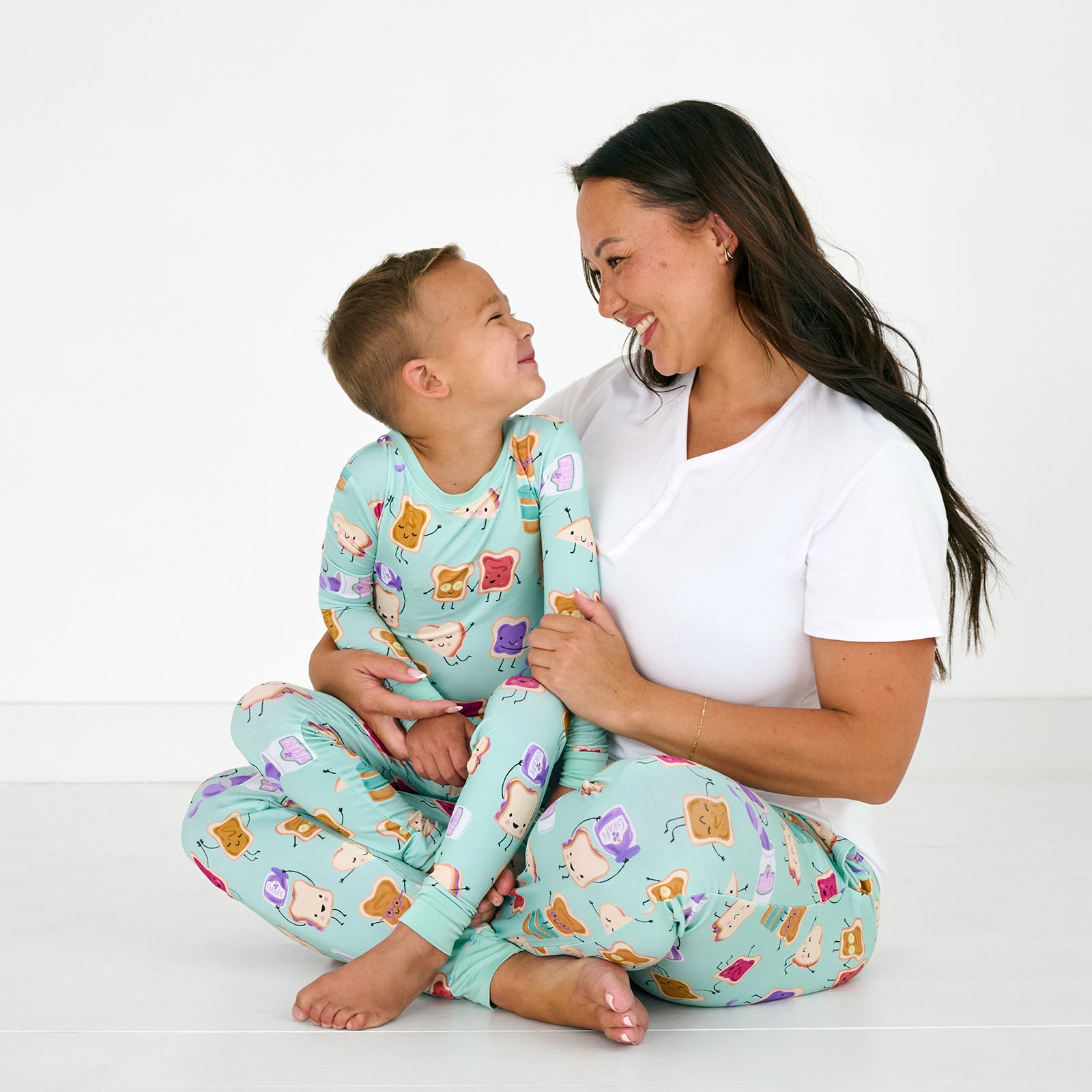 Sitting mother and son wearing matching Lunch Buddies pajamas