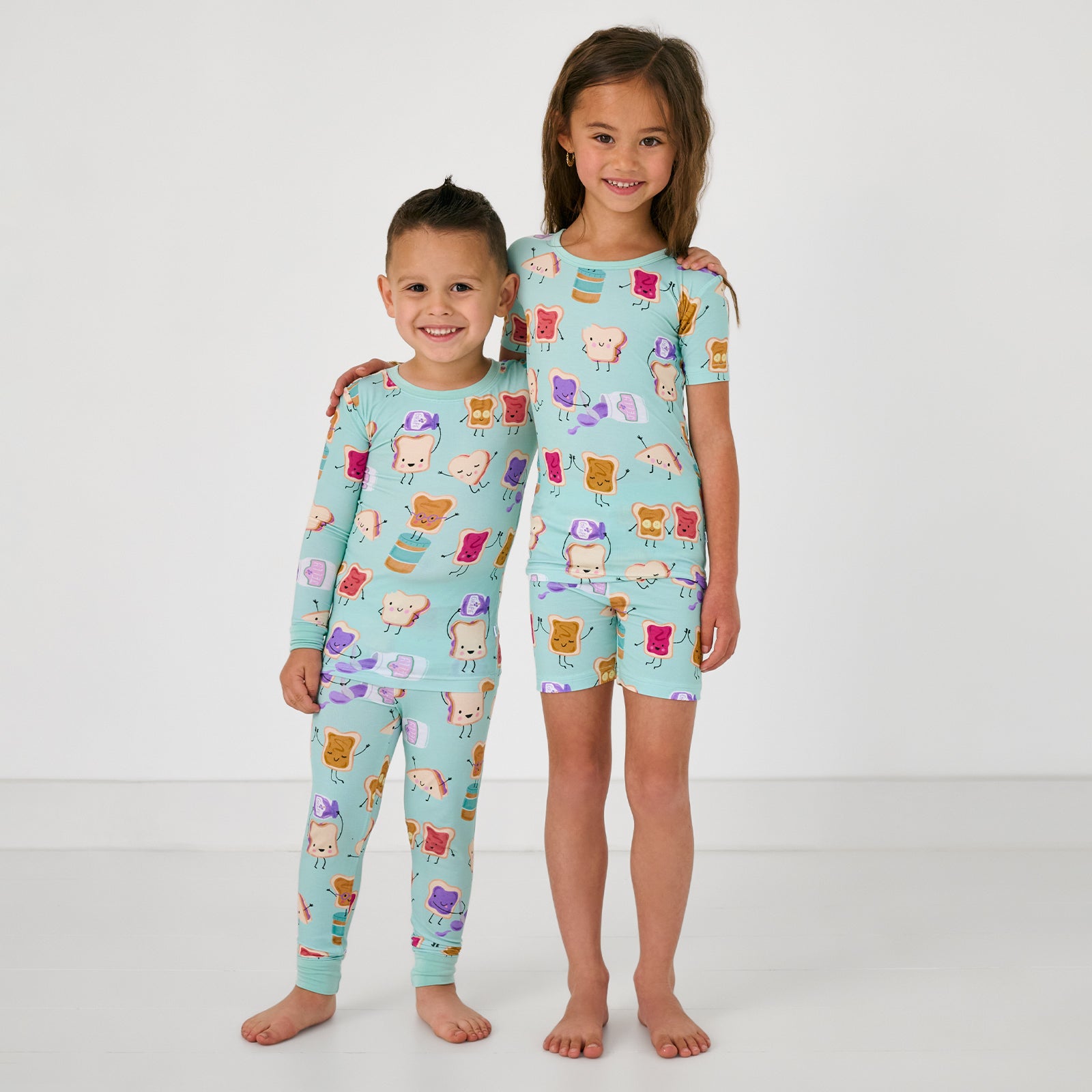 Two children wearing matching Lunch Buddies Two-Piece Pajama Sets