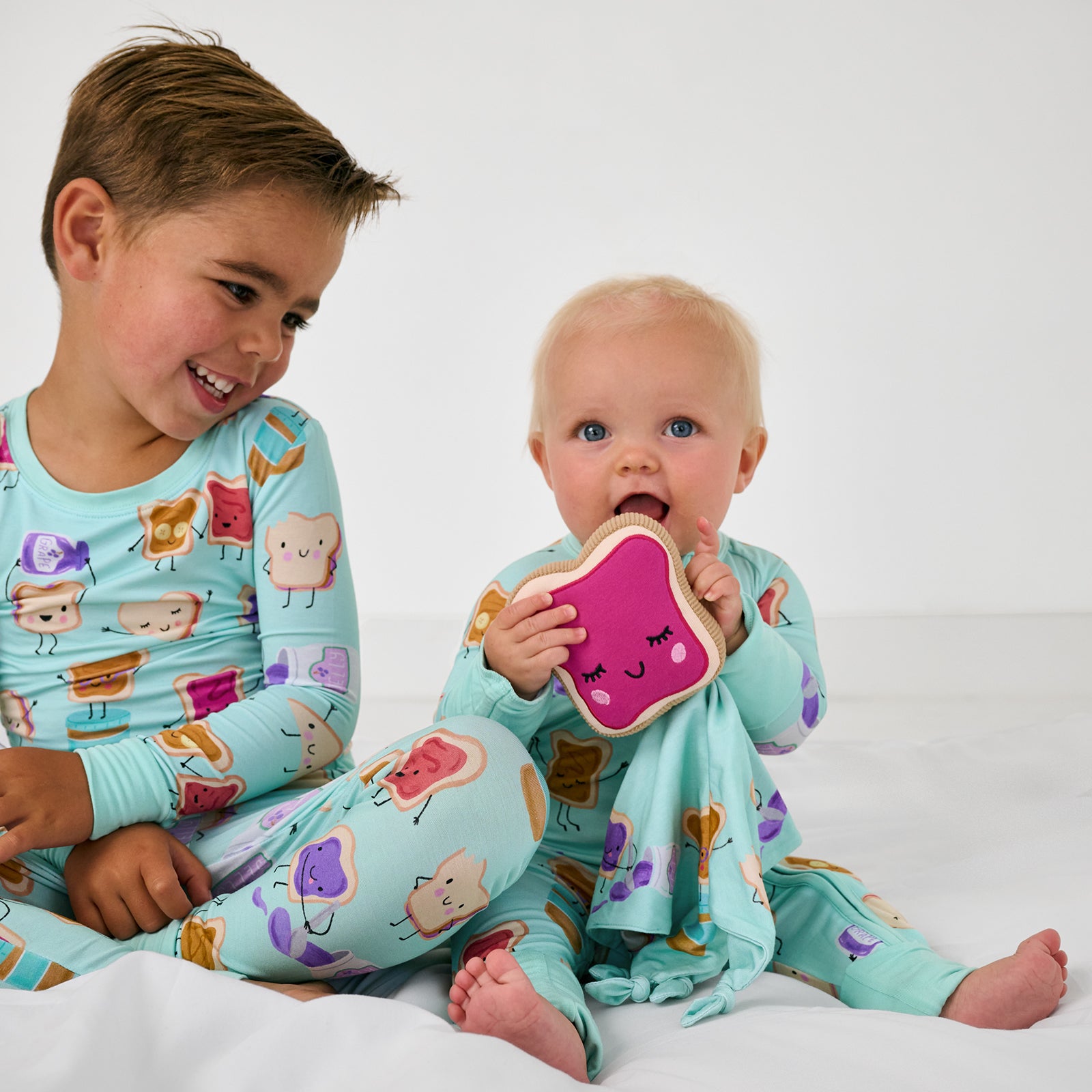 Two sitting children wearing Lunch Buddies bamboo pjs