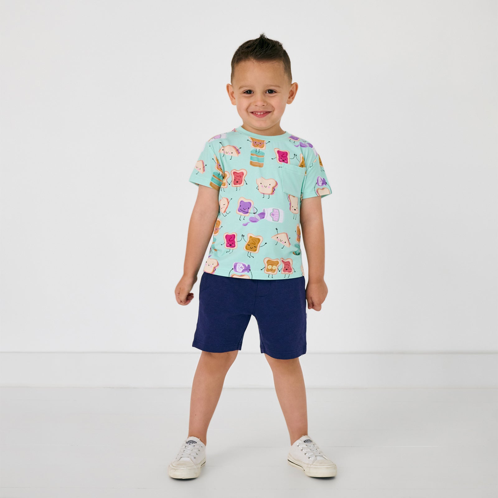 Standing child wearing the Lunch Buddies Relaxed Pocket Tee with classic navy shorts