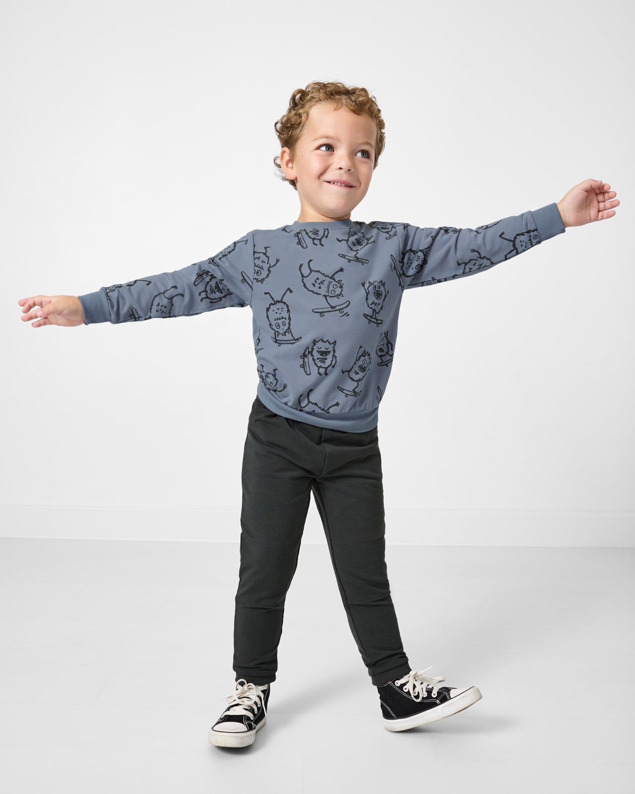 Posing boy wearing the Monster Moves Crewneck Sweatshirt with black joggers