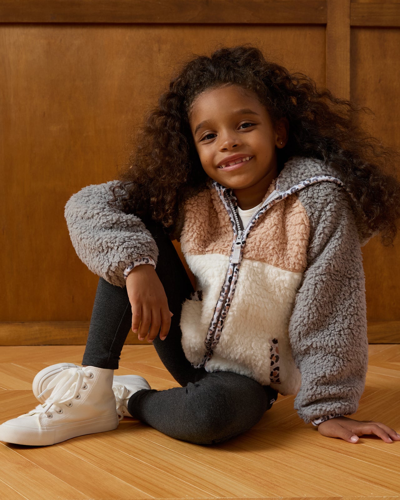 Sitting girl wearing the Morning Fog Sherpa Jacket and heather black legging
