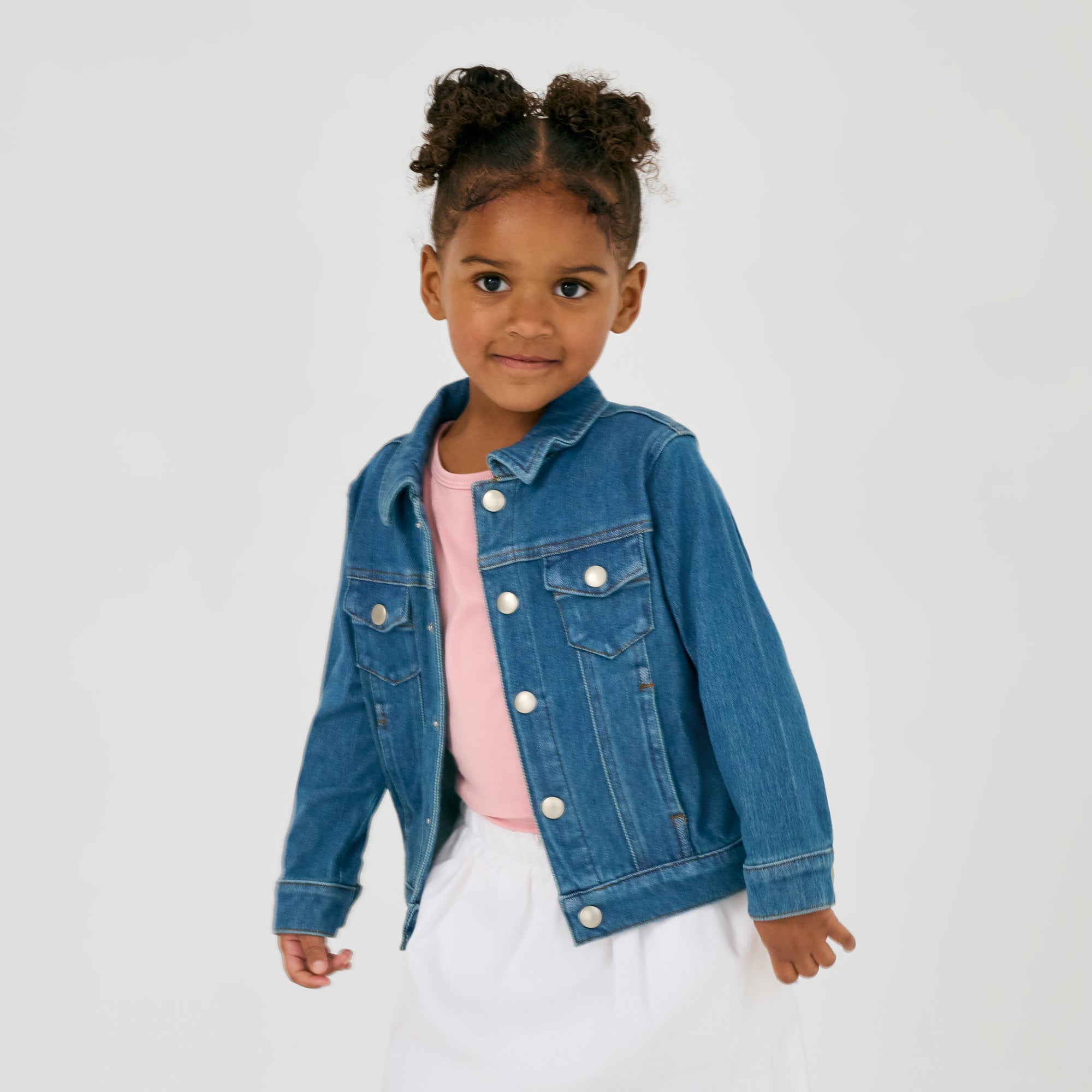 Girl wearing the Midwash Blue Denim Trucker Jacket layered of a mauve blush tee