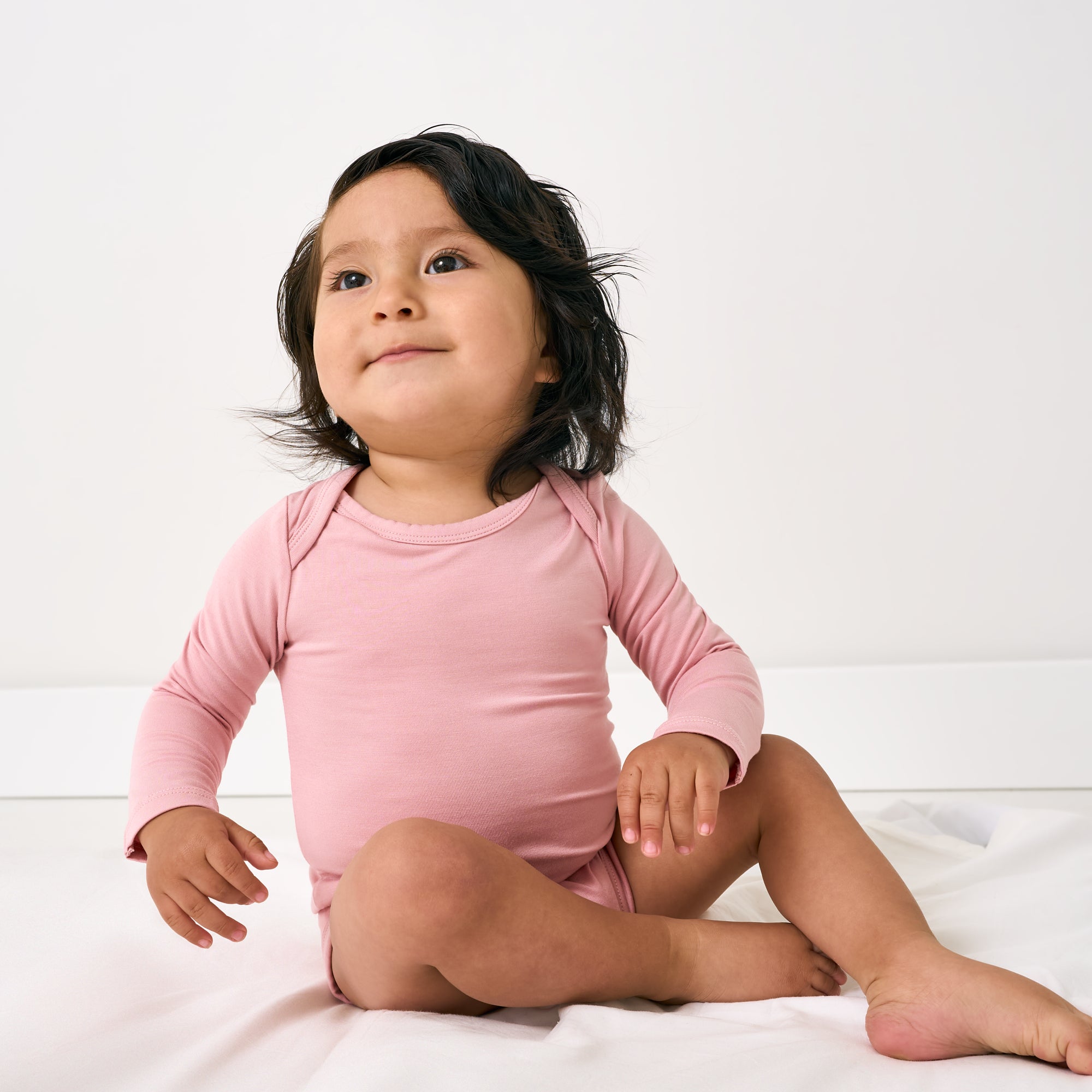 Sitting child wearing the Mauve Blush Long Sleeve Bodysuit