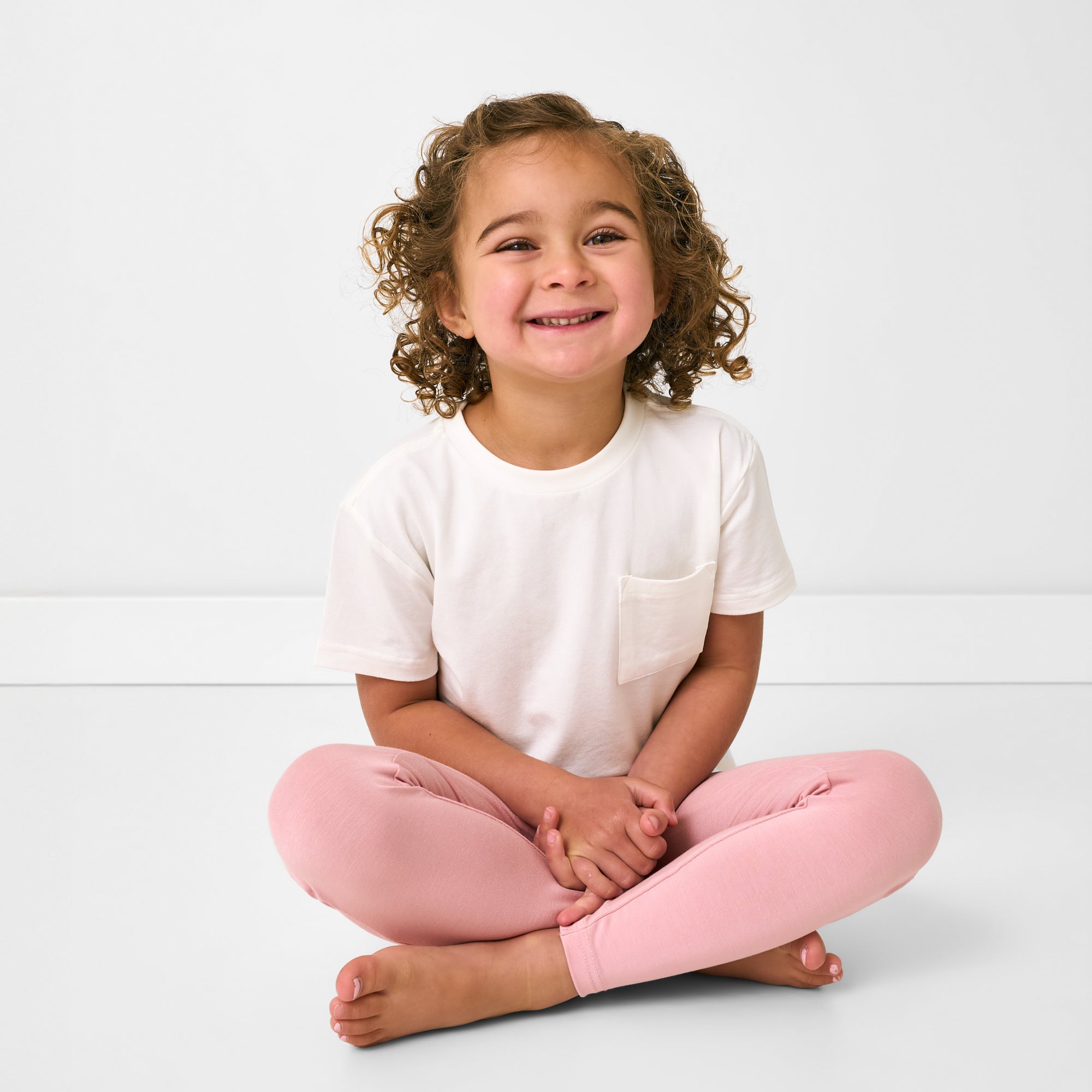 Sitting child wearing the Mauve Blush Legging with a white pocket tee