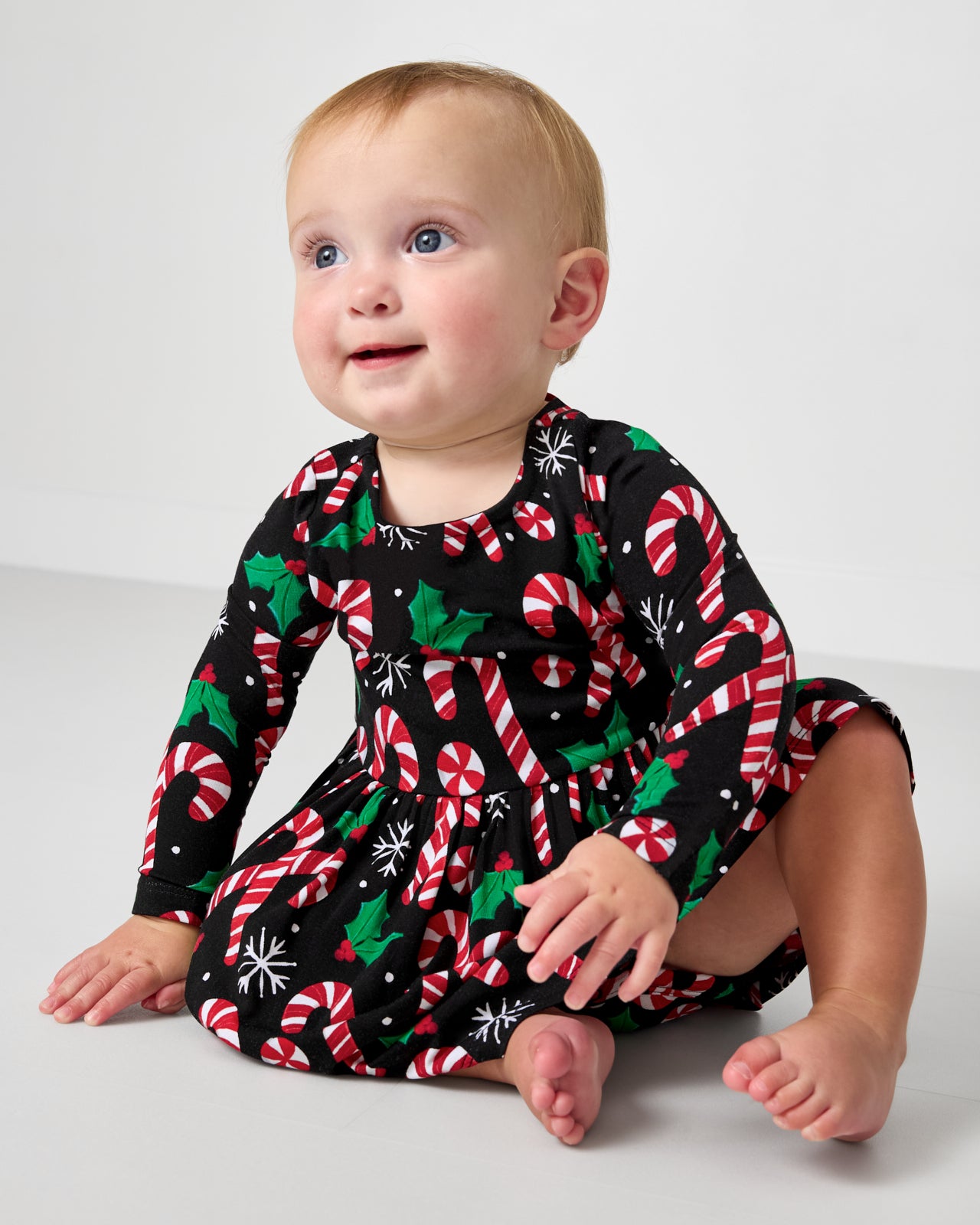 Sitting baby wearing the Merry Mints Bow Back Skater Dress with Bodysuit