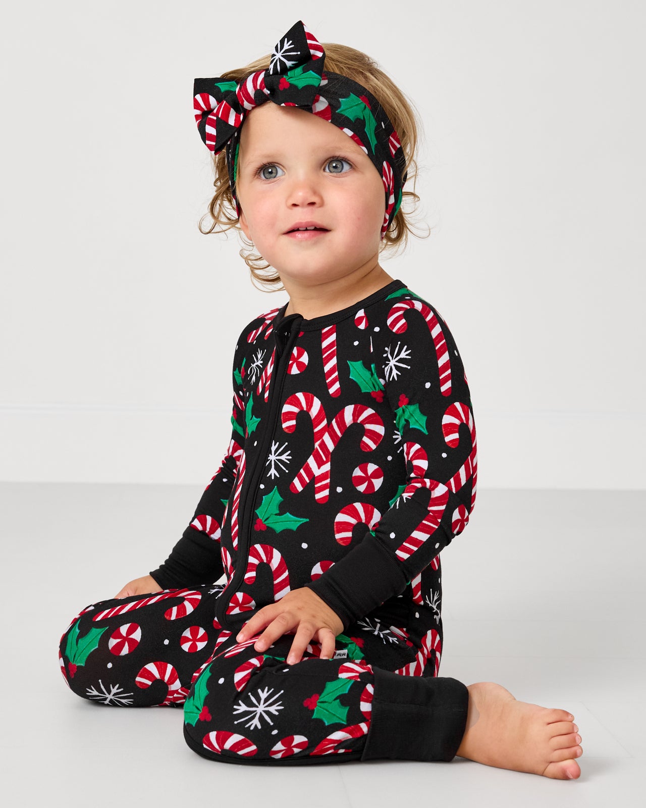 Toddler wearing the Merry Mints Luxe Bow Headband with the matching zipper pajamas