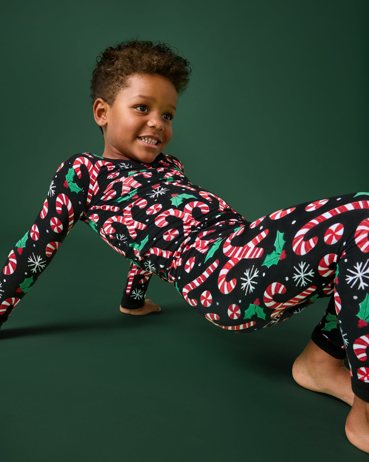 Child wearing a festive onesie with candy cane pattern on a green background