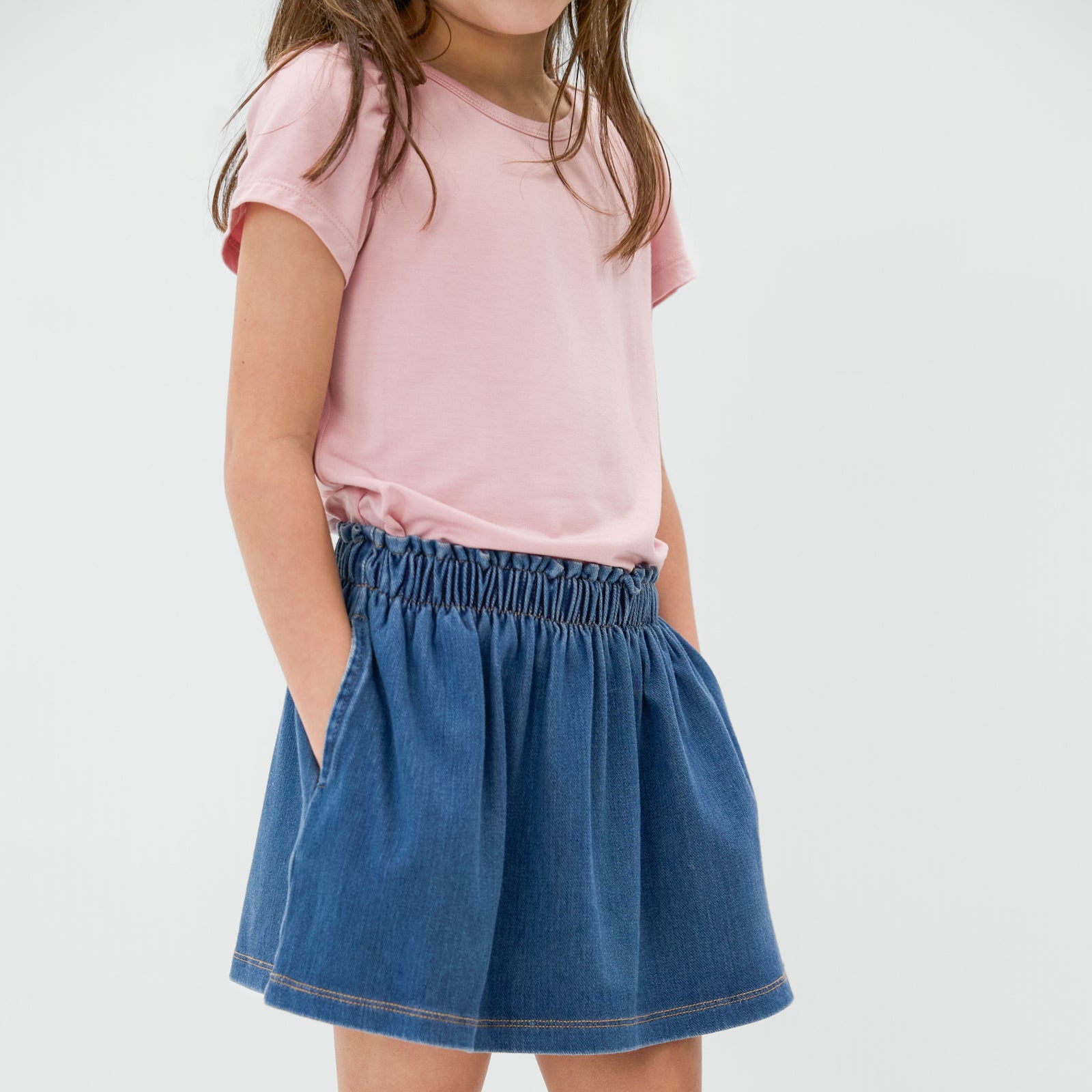 Close up of child wearing the Midwash Denim Skort with a pink bamboo top