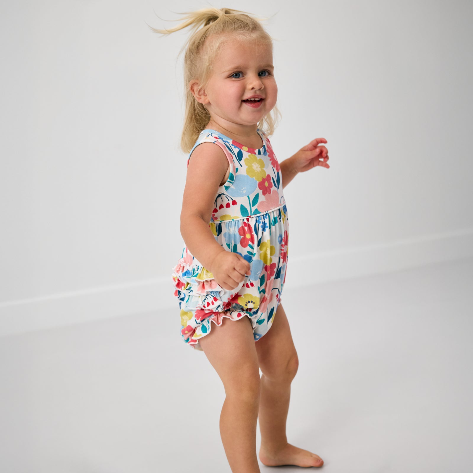 Standing toddler wearing the Midsummer Meadow Bubble Romper