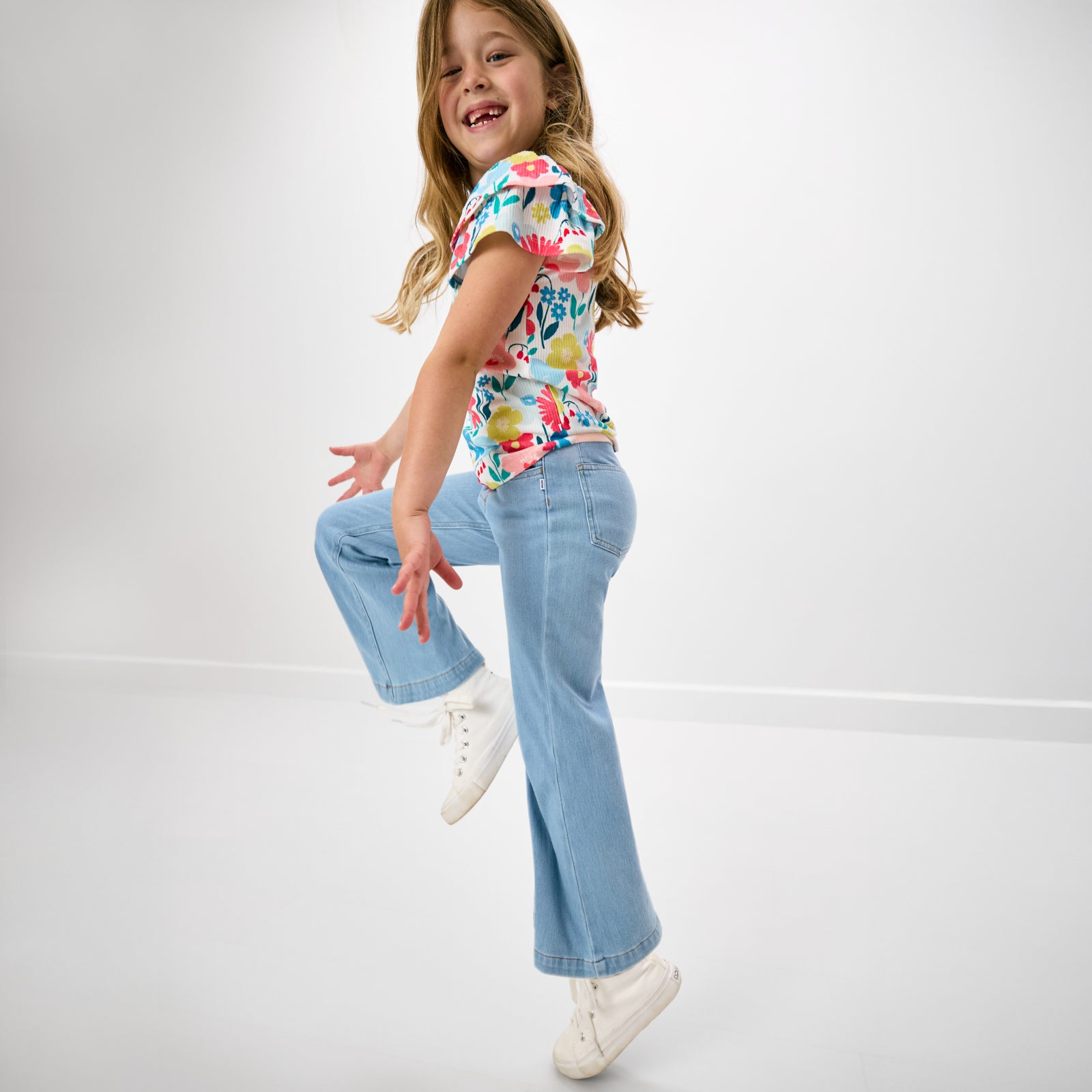 Child in motion wearing the Midsummer Meadow Double Flutter Tee with wide leg denim pants