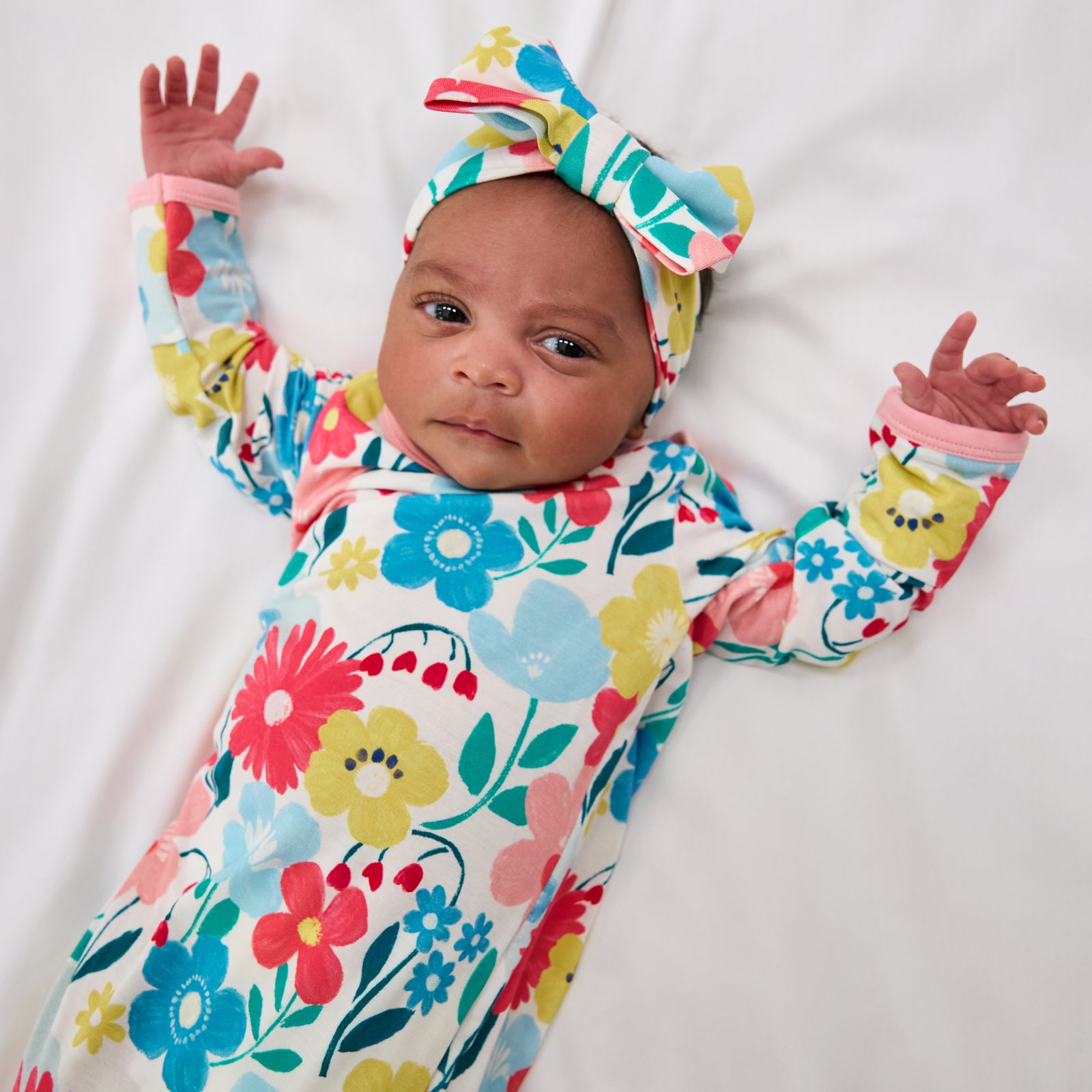 Close up of baby wearing the Midsummer Meadow Infant Gown with a matching luxe bow headband