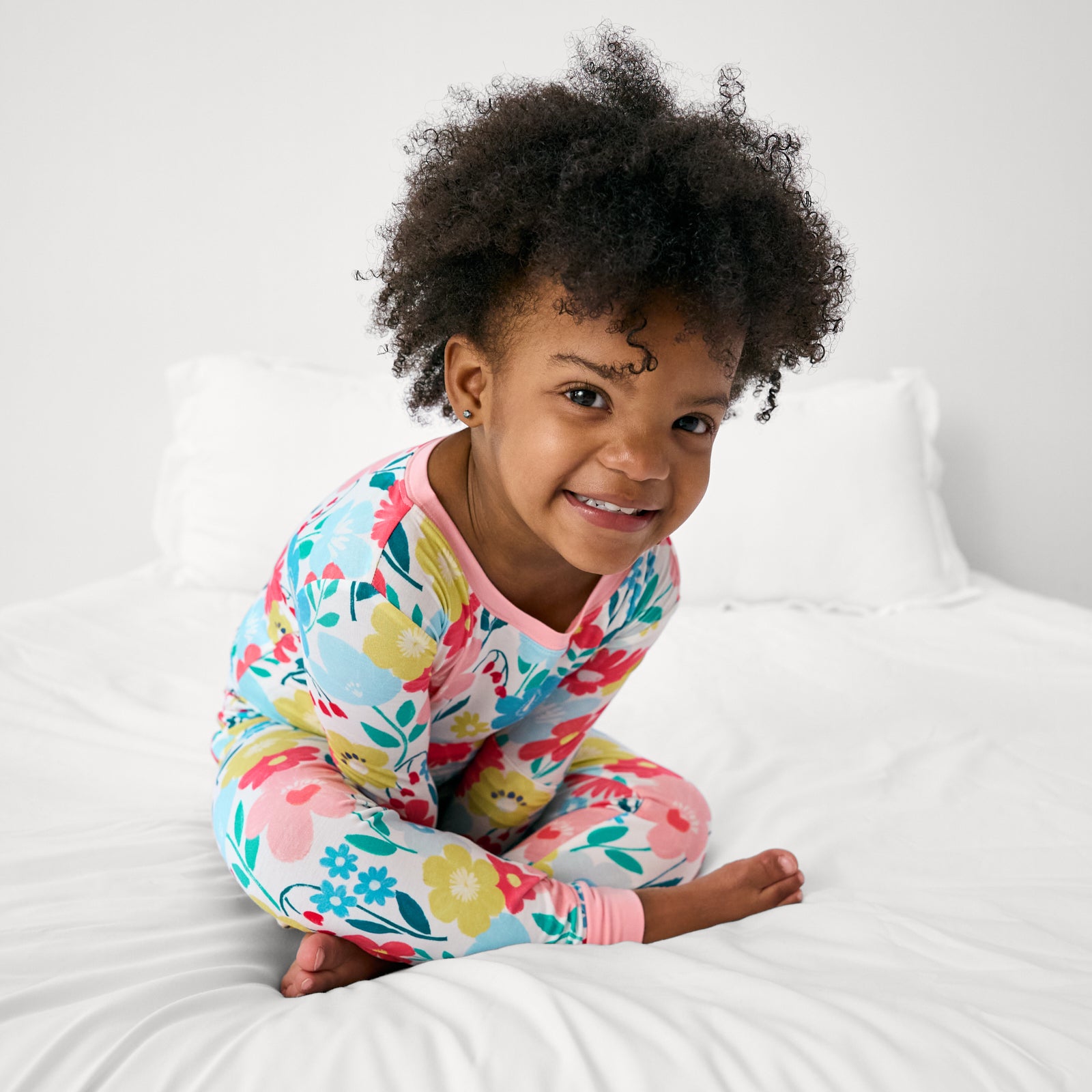 Girl sitting on a bed wearing the Midsummer Meadow Two-Piece Pajama Set