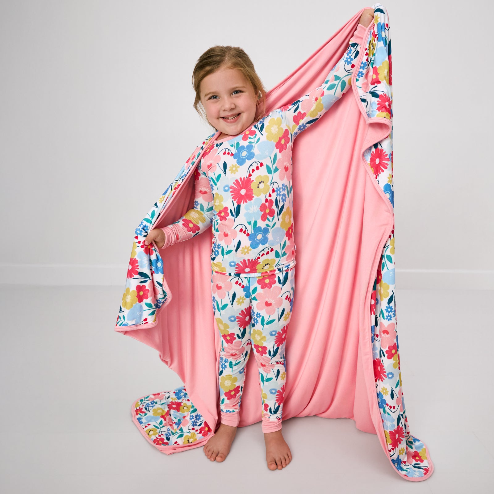 Standing girl holding up the Midsummer Meadow Large Cloud Blanket®